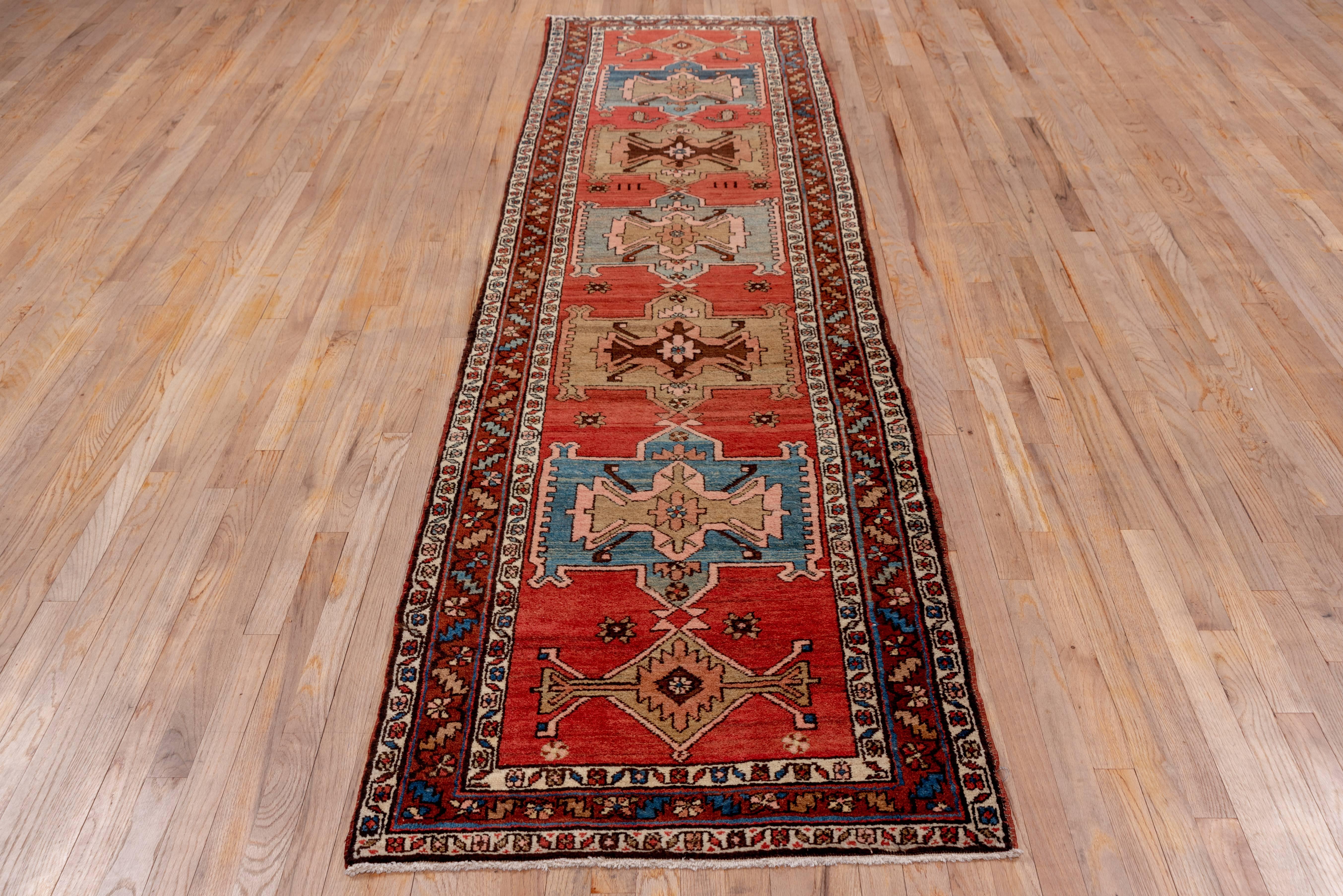Serapi rugs are a high grade of Heriz weaving's. The well abrashed soft madder red nearly open ground has a pole medallion of seven large and small connected rectangular and lozenge form elements in turquoise, camel, beige, lime and dark brown. The