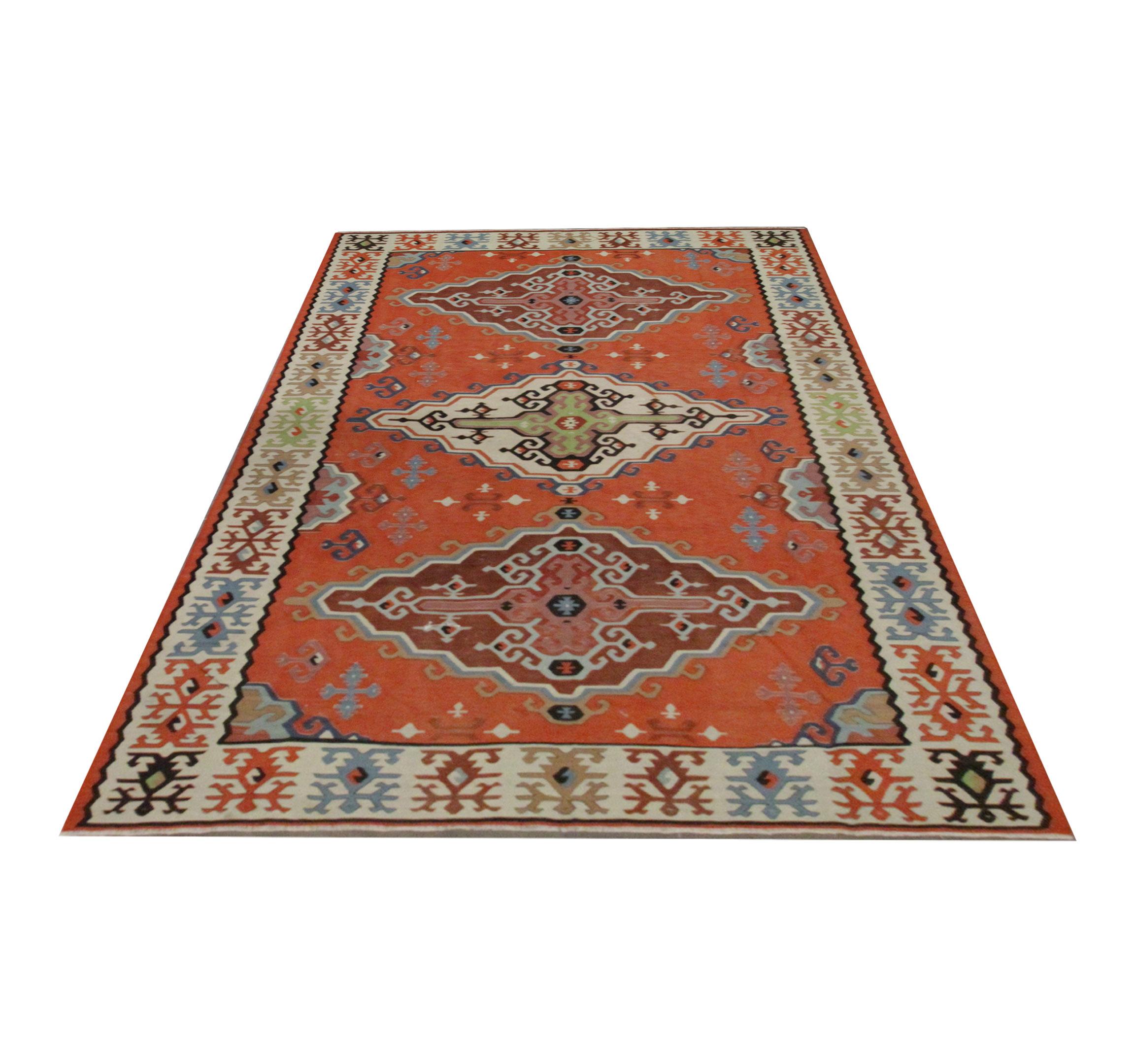 This beautiful handmade kilim is a Serbian, Pirot rug woven in the 1930s. The design features a rich rust background with a trio of medallions in cream, brown and pink accents. This has then been framed by a cream border with a repeating motif