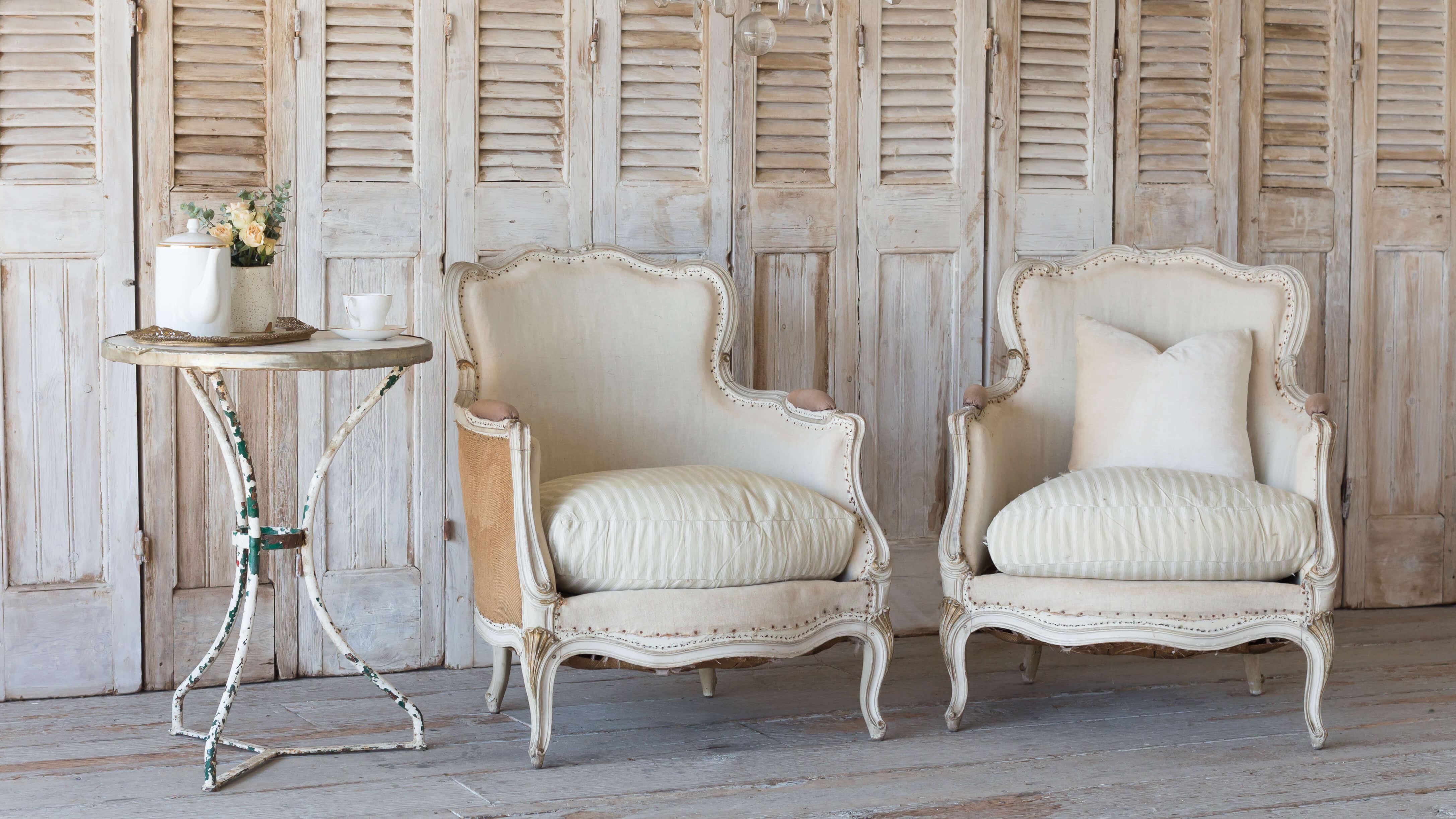 Antique French bergeres in worn creamy white original finish. Beautiful curving carvings and serpentine shape. Original muslin and burlap upholstery with antique sea green and cream stripe ticking.