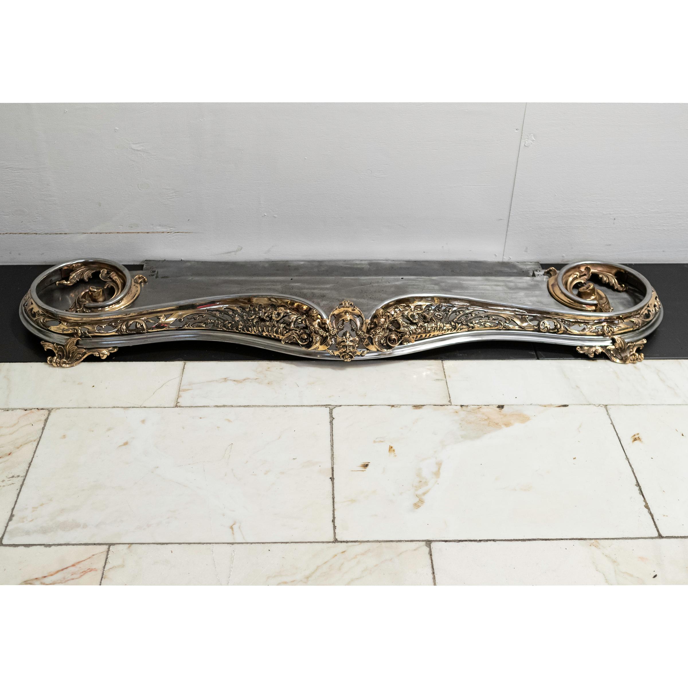 Highly ornate, this antique brass fireplace fender is in the Louis XV style with elaborate decorative features including florals, foliate scrolls and mermaids. The polished steel is complimented by abundant brass detailing.

Dimensions
Overall:
