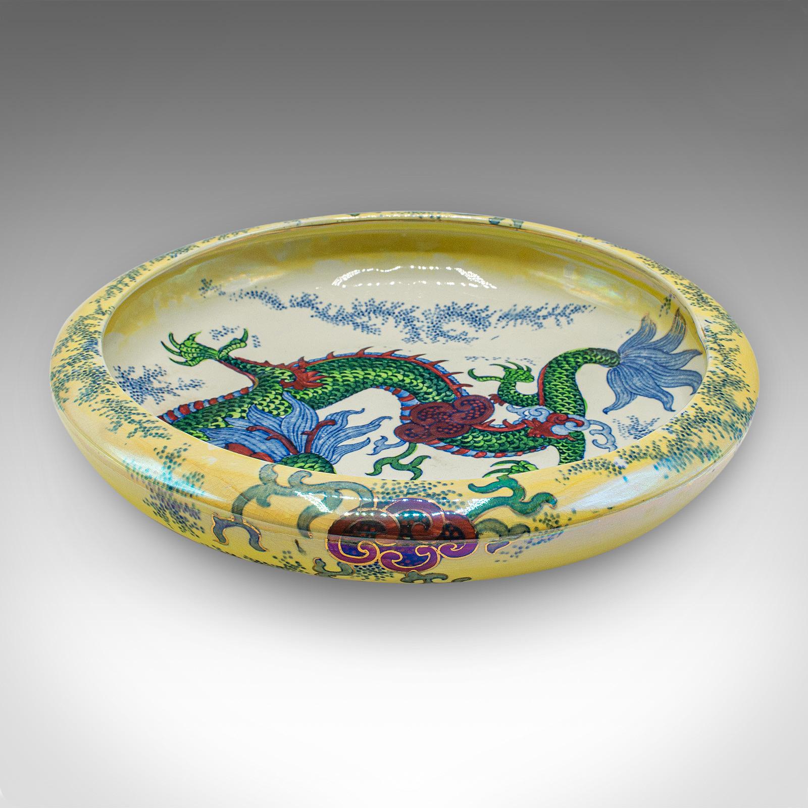 This is an antique serving bowl, an English ceramic fruit dish with Oriental taste, dating to the early 20th century, circa 1920. With dazzling colour and striking dragon motif, this decorative dish delivers superb early 20th century