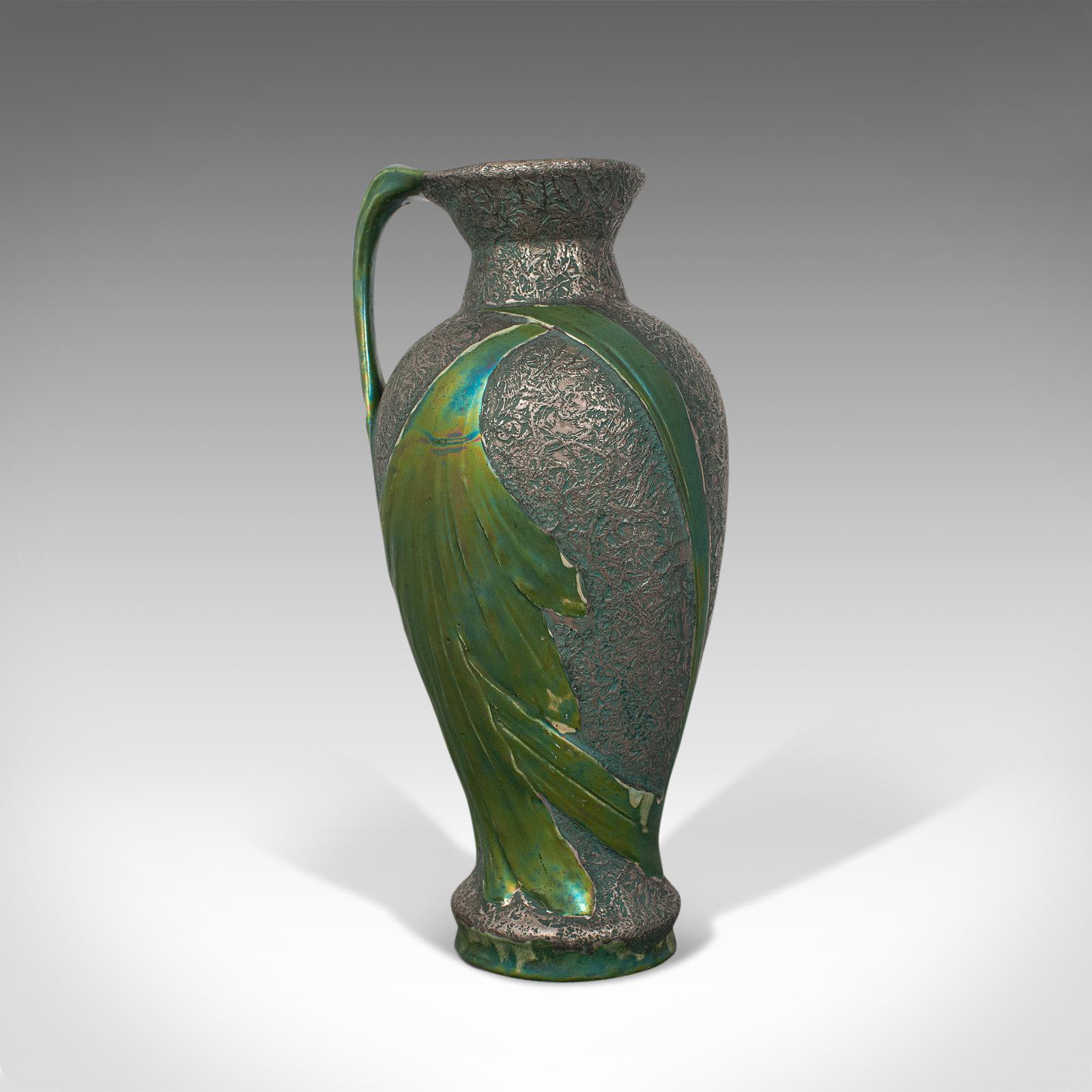 This is an antique serving ewer. An Austrian, ceramic amphora or jug, dating to the Art Nouveau period, circa 1900.

Alluring verdant hues and organic form
Displaying a desirable aged patina - free of marks and losses
Ceramic presented in ornate