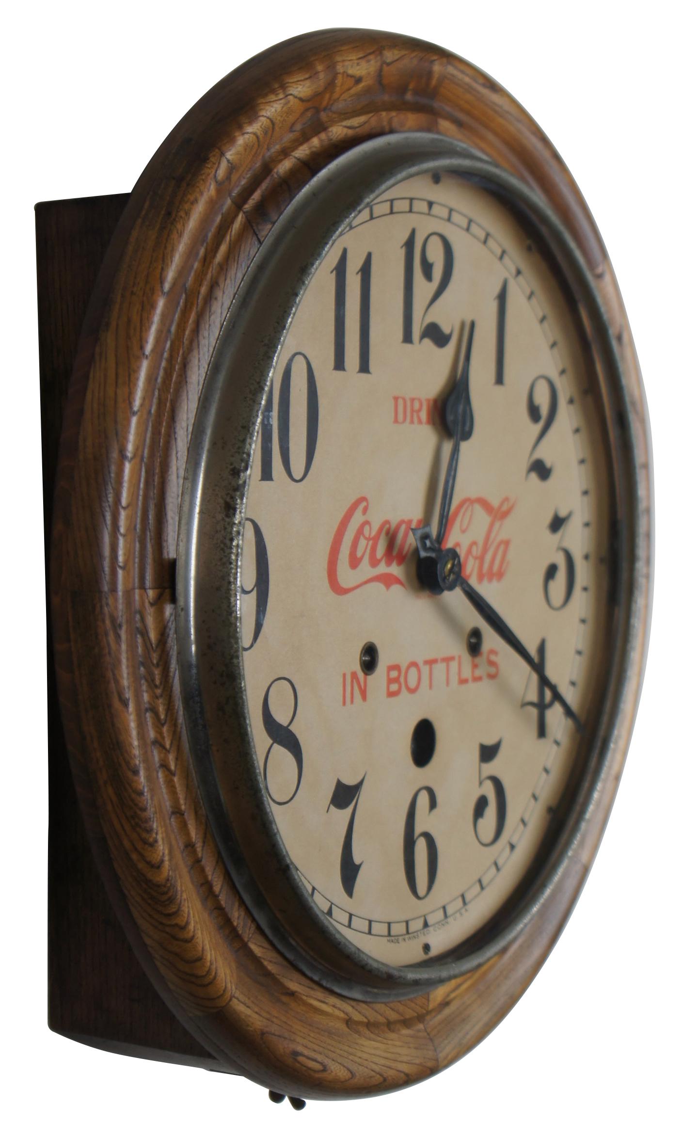 Antique Seth Thomas round oak wall clock with “Drink Coca-Cola in Bottles” face. Circa 1900s.  Features a neat design with peekaboo pendulum and key.  
