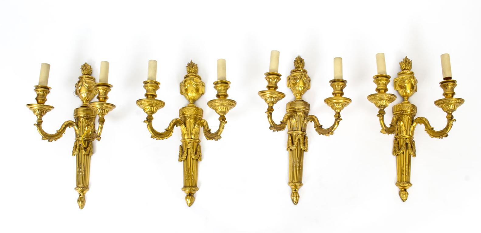 This is a beautiful set of four good sized Adam Revival ormolu twin branch wall lights, dating from the mid-19th century.

The lights feature classical Regency elements with anthemion and classical flaming urn, with flame and scrolling drapery cast
