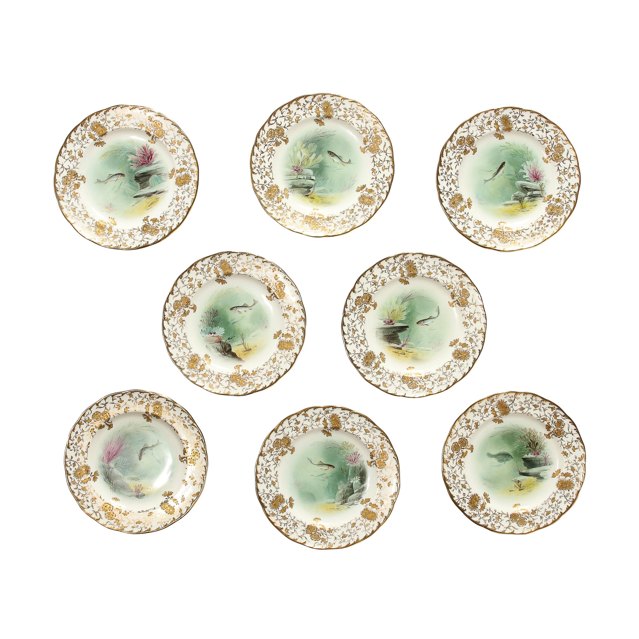 Cette exquise  Cet ensemble de huit assiettes en porcelaine de Minton peintes à la main et représentant des poissons, signé A. Holland, provient d'Angleterre et date d'environ 1900. Le bord de chaque assiette présente des motifs floraux dorés