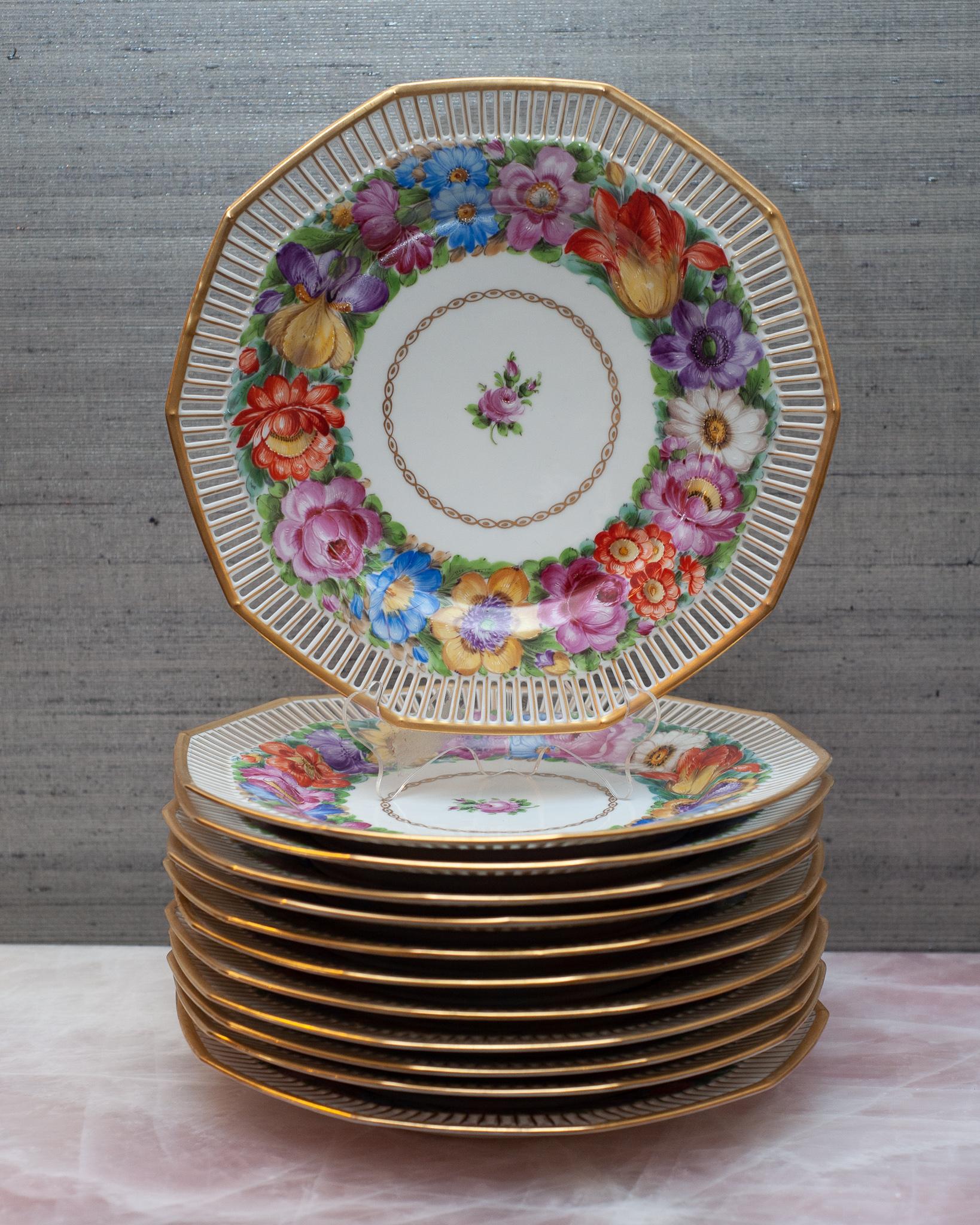 A stunning and ornate set of 12 floral dinner plates by Dresden with gilt detail produced in the early 20th century. What makes these so special is the elaborate cut out gallery edge. Franziska Hirsch started her porcelain painting business in