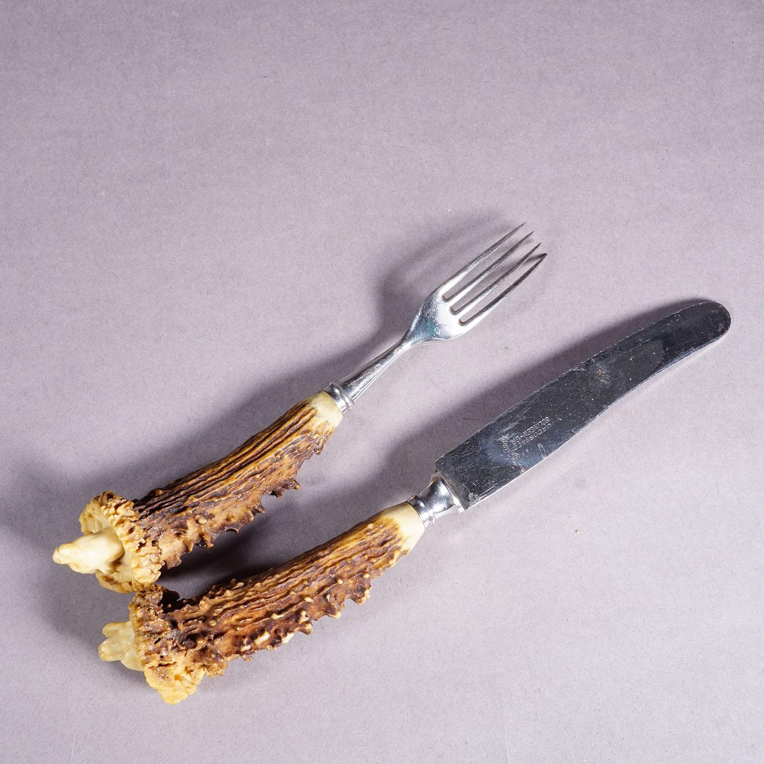 Antiguo Juego de Cubiertos Rústicos del Siglo XIX con Mangos de Cuerno Tallados

Un raro juego de cubiertos antiguos de cuchillo y tenedor. Las empuñaduras son de asta de ciervo con cabezas talladas a mano de un oso y una gamuza en su extremo. Las