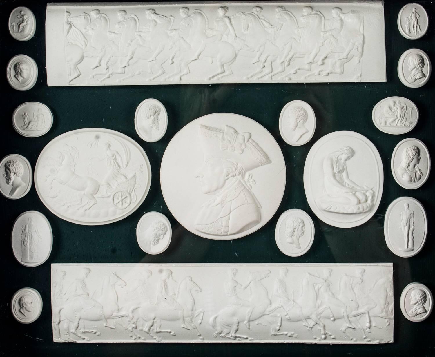 An arrangement of framed plaster Grand Tour intaglios of various sizes dating from the early 19th century.

The intaglios are beautifully mounted on a plush green ground in a boxed frame and consist of twenty-one circular, oval and