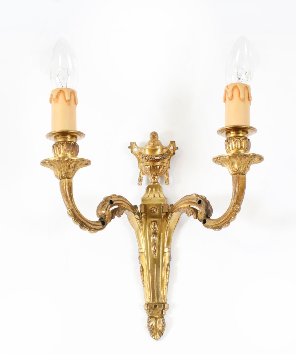 This is a fine set of three antique twin branch ormolu wall lights with urn shaped finials, leaf-sheathed scroll branches and fasces backplates dating from Circa 1900.

Add an elegant touch to your home with this decorative set of ormolu wall