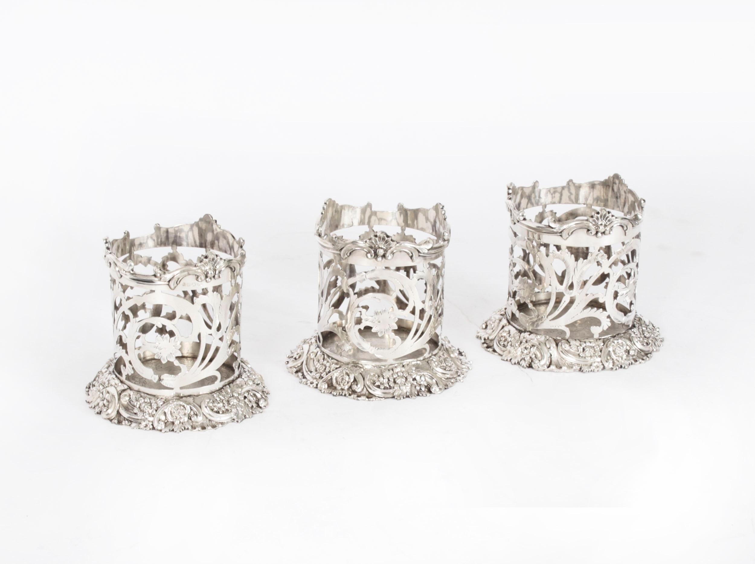 This is a lovely set of three Victorian silver-plated wine bottle coasters /  holders, circa 1870 in date. 
 
They feature pierced cylindrical sides with bases heavily decorated with embossed and engraved foliate and floral decoration.
 
The unique