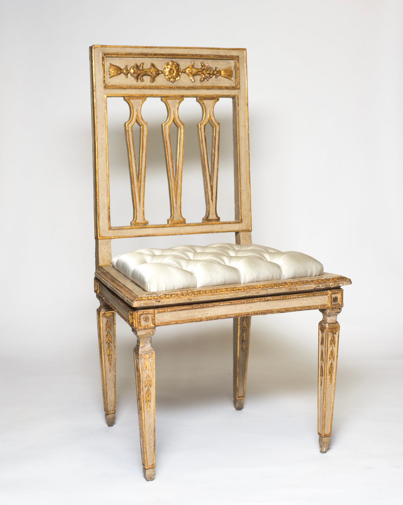 A set of four antique Florentine chairs with ornate carving and reupholstered in silver silk satin with a tufted design.