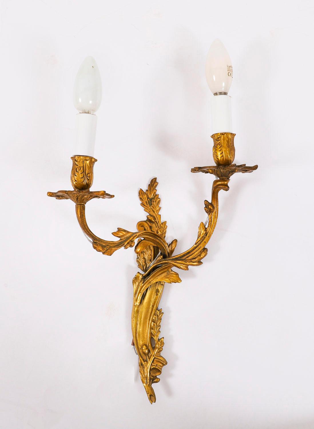 Il s'agit d'un superbe ensemble de quatre appliques murales anciennes en bronze doré rococo, datant d'environ 1870.

Les plaques arrière présentent des branches en volutes avec des décorations florales et des douilles de bougies. 

Achetées dans une