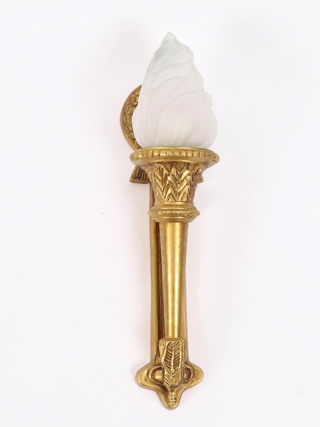 This is a superb antique set of four stylish French Neo-classical ormolu & glass flaming torch wall lights, circa 1920 in date.

Each has an ormolu foliate and ribbon backplate holding a frosted glass torch, the quality and craftsmanship is 