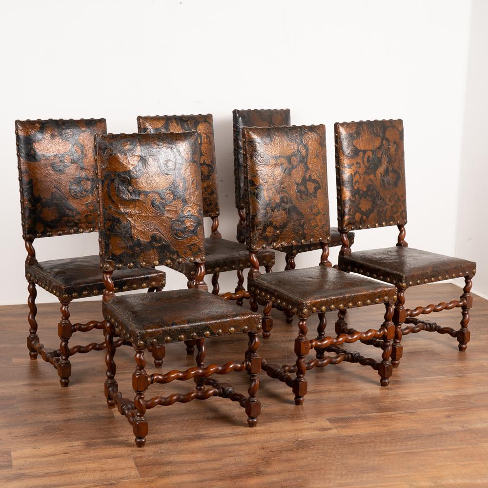 Impressive set of six embossed and hand-painted leather dining chairs with oak barley twist legs and stretchers.
Elaborate details abound in each chair, with intricate embossed patterns and flourishes in the leather that are hand-painted in black,