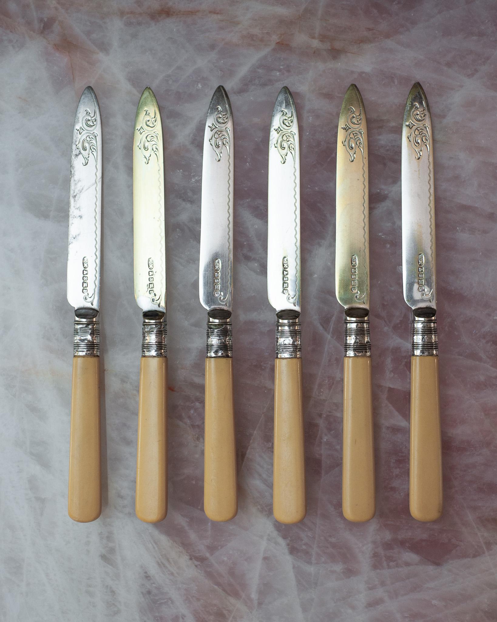 Un bellissimo set di 6 coltelli Sheffield con manici in bachelite, ghiere in sterling e lame in argento galvanizzato. Ogni ghiera ha il marchio dell'argento sterling e le lame presentano diversi gradi di usura della placcatura in argento. Ogni