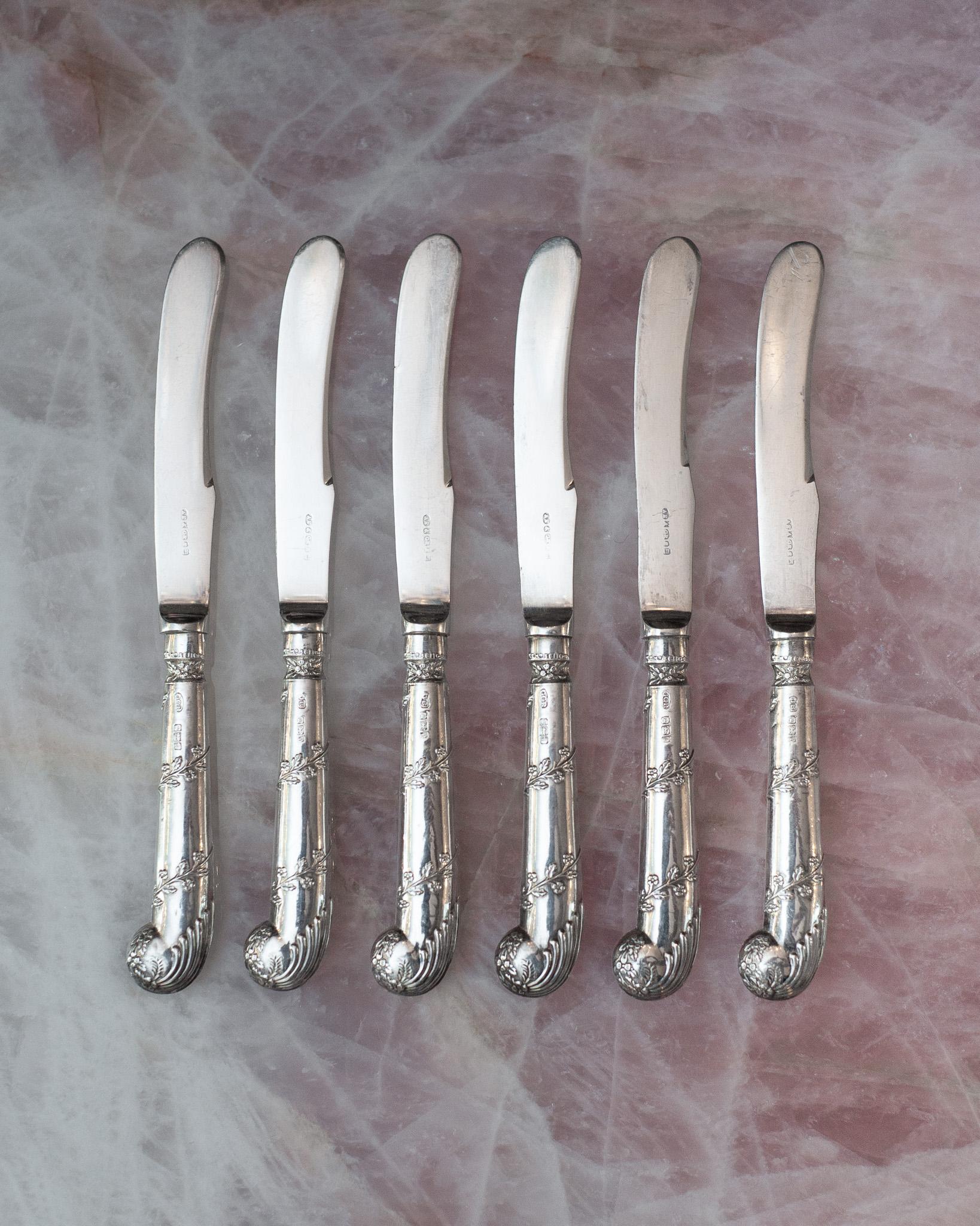 Un magnifique ensemble de 6 couteaux à beurre Sheffield avec des manches en forme de pistolet en argent sterling enveloppés d'une couronne de fleurs, et des lames en argent EP. Chaque poignée est poinçonnée pour l'argent sterling et porte des
