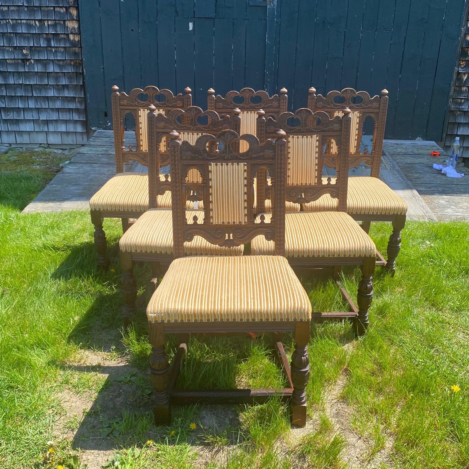 Beautiful and sturdy set of 8 dining chairs in the English Country Jacobean style. Crafted with intricate carved wood detail, these antique chairs exude a timeless charm that will elevate the aesthetic of any space. The neutral color of the brass