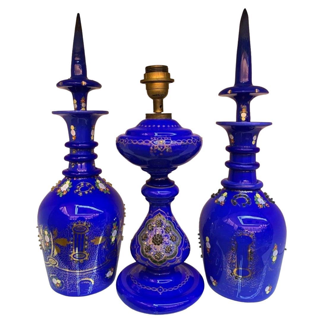 Antique large pair of dark blue decanters made of high quality opaline glass, decorated with gilding, enamel and jewel decoration
together with a matching oil lamp with brilliant enamel decoration
manufactured in the 19th century for the Islamic