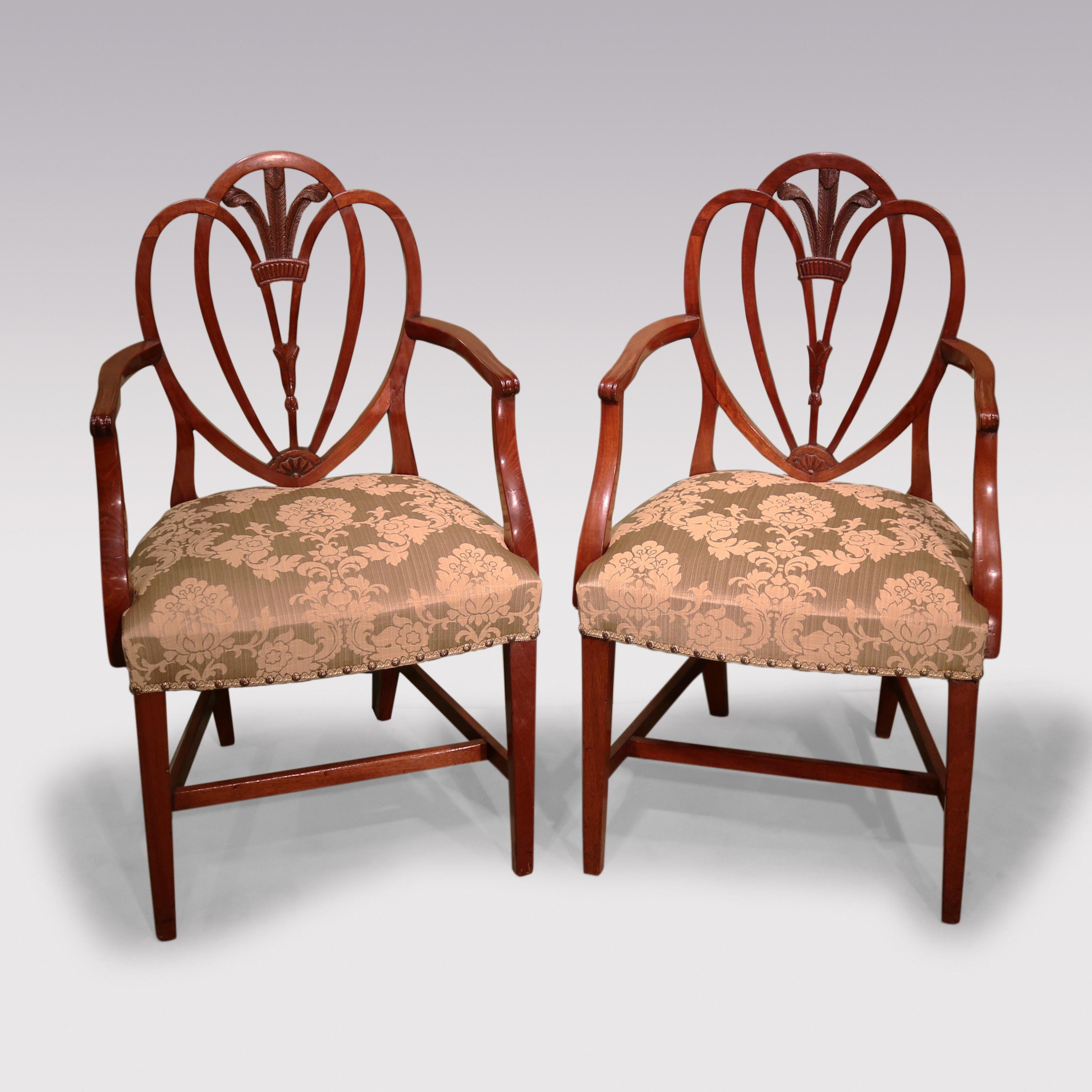 A set of 6 single and 2 arm Hepplewhite period mahogany Dining Chairs, having triple arched backs enclosing carved Prince of Wales feathers, with set-back arms above stuffed-over seats supported on square tapering legs with “H” stretchers.