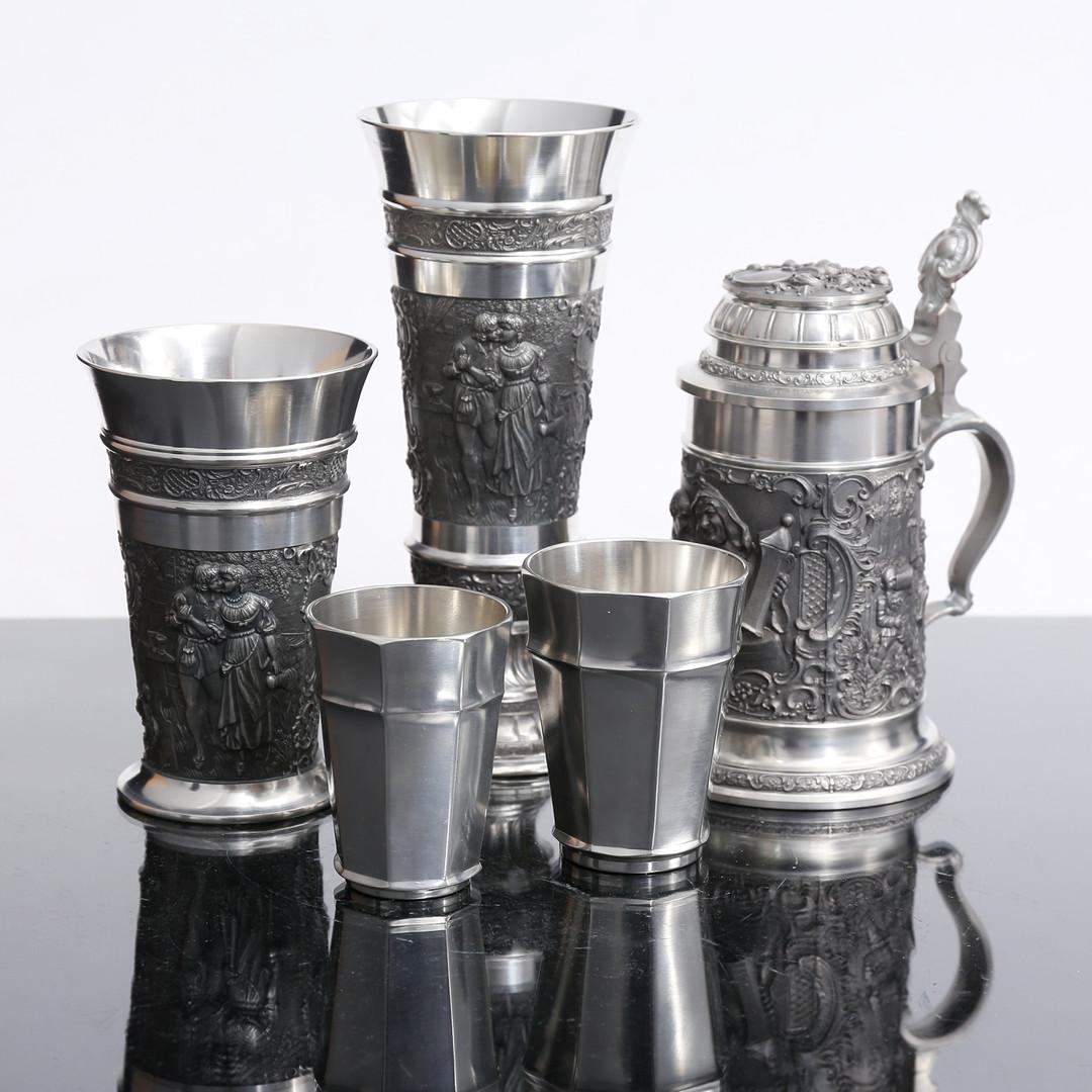 Conjunto de cinco objetos decorativos antiguos de estaño alemán Defregger Beer Stein Decorative Cup Bowl , taza de cerveza decorativa o vaso de cerveza con tapa, prensados, fundidos y cincelados. Circular, pies curvos con bisagra. estampado, altura