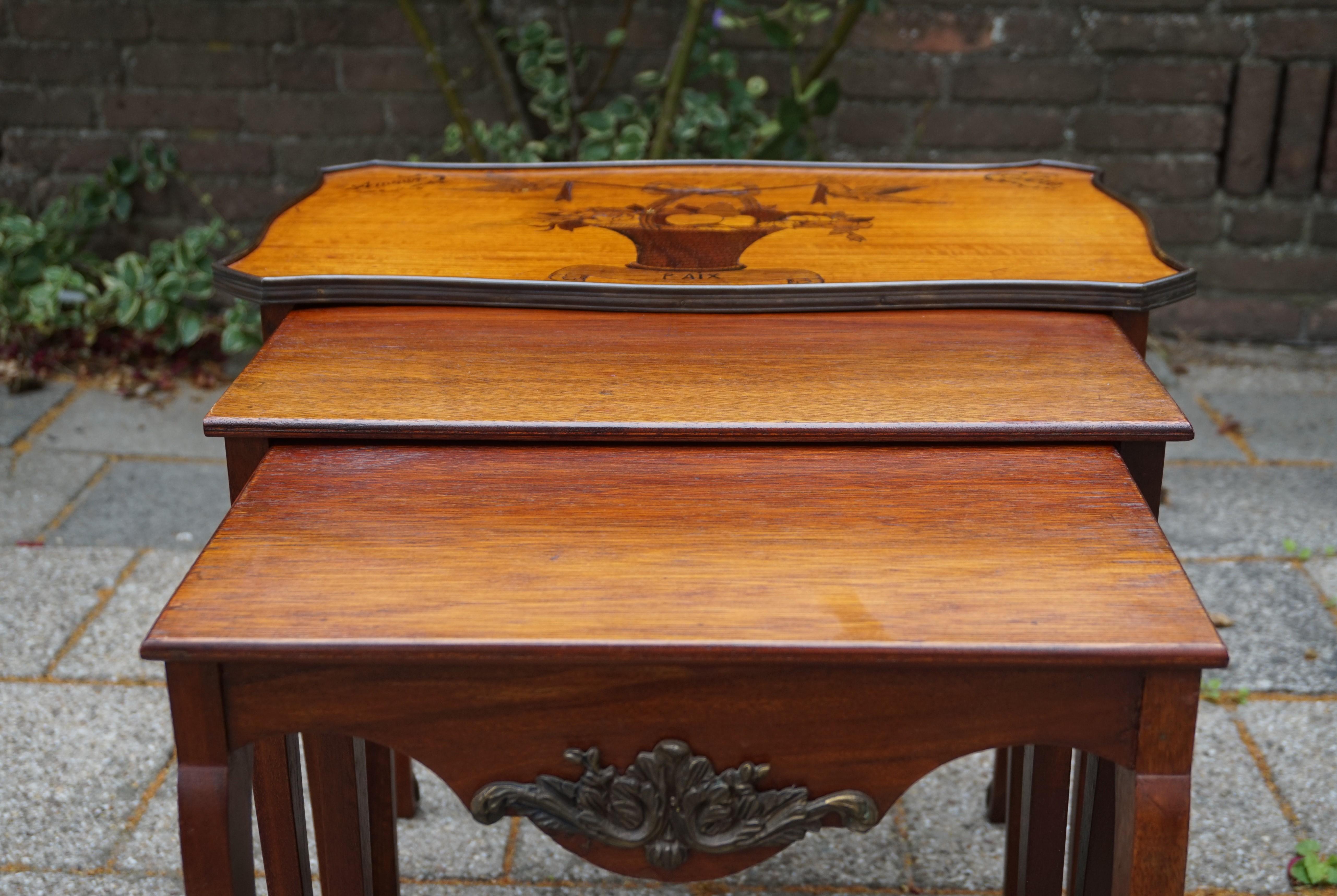 Unique set of stacking tables with marvelous inlay and maker's mark.

This marvelously handcrafted set of 3 tables from the early 1900s has the most elegant shape and patina. The tabletop of the largest table is made of satinwood and the message is