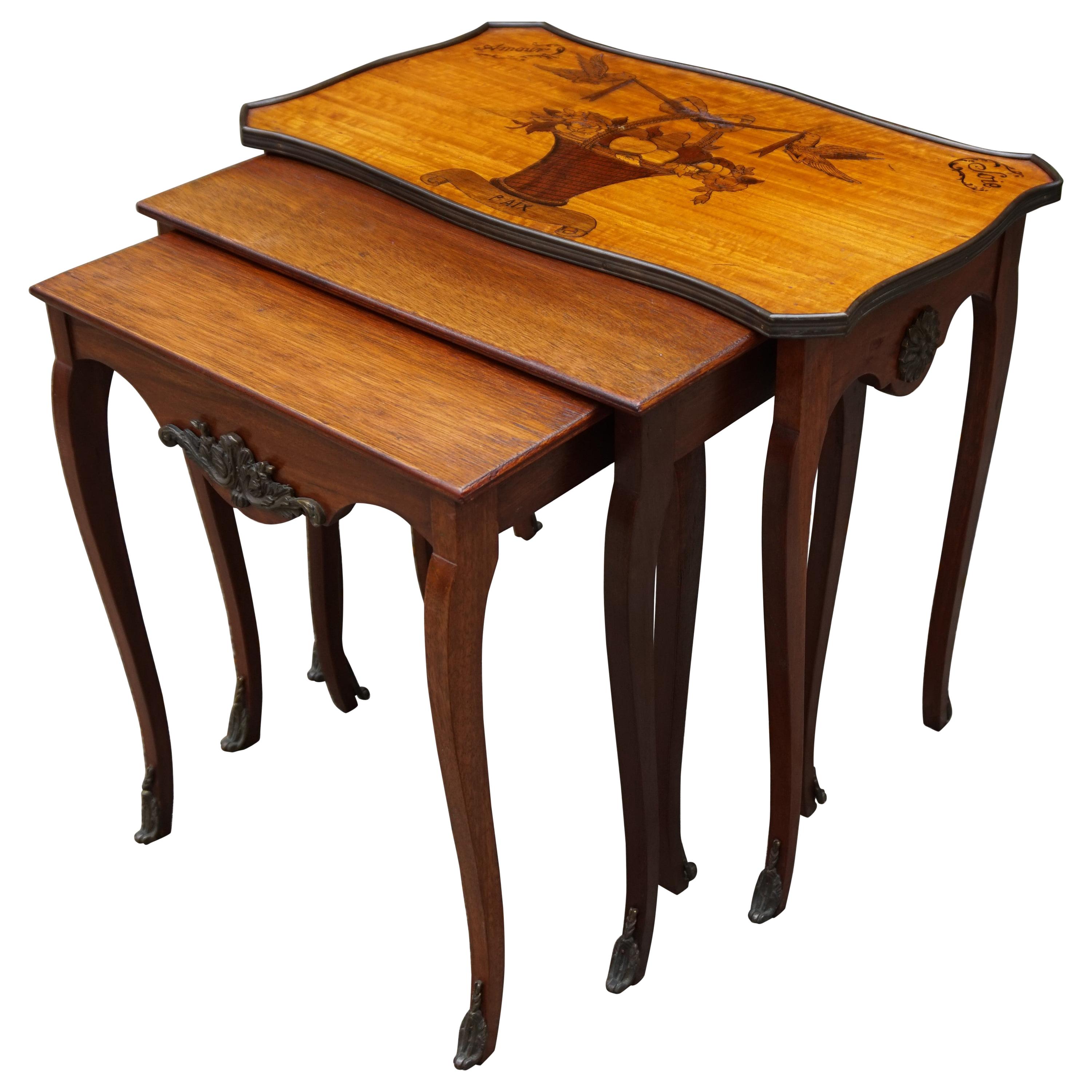 Antico set di tavolini da nido in legno di noce con. Ornamenti intarsiati a tema amore e bronzo