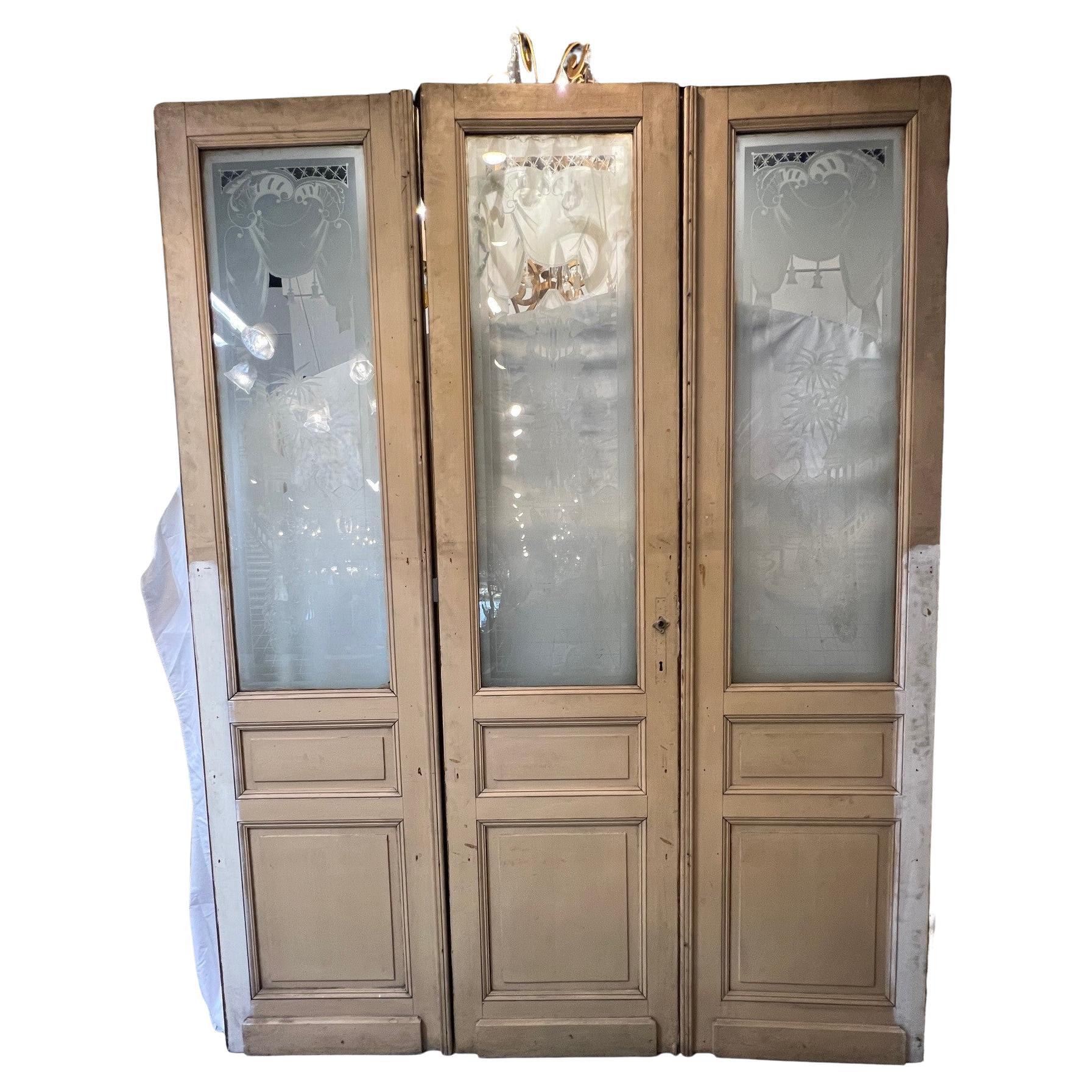 Salvaged from an estate in France, this is a beautiful set of doors with etched glass and raised wood panels. The etched glass is very ornate with the center door featuring a vase with flowers on a balcony overlooking a body of water. The doors to