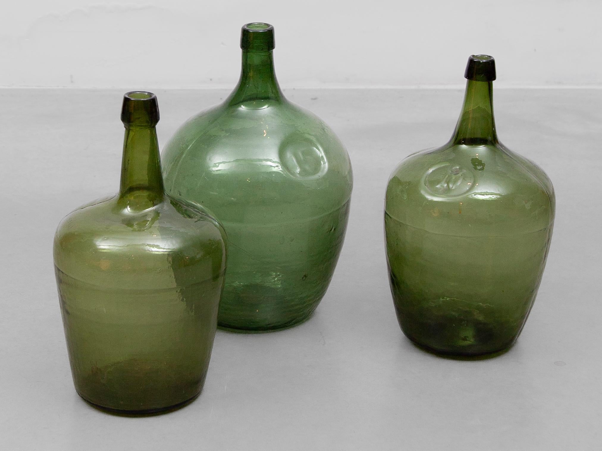 Set of 3 mount blown green glass bottles packing glass, carboy for wine and essence.
The term 