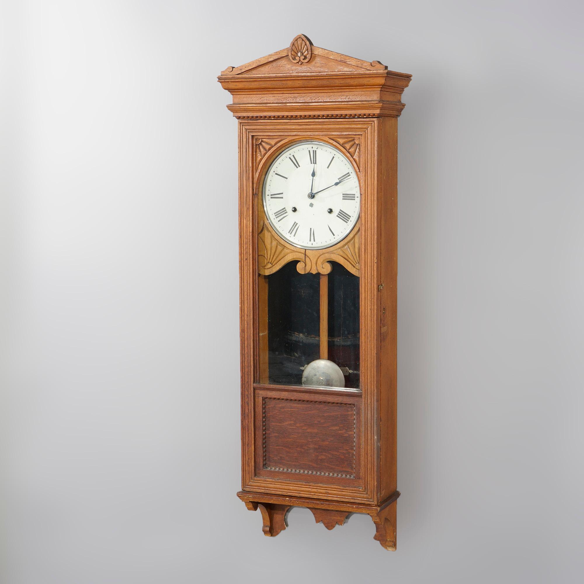 An antique regulator wall clock by Seth Thomas offers oak case with architectural form having central stylized carved shell, sunburst and foliate elements, c1900

Measures- 50.5''H x 17''W x 7.5''D.