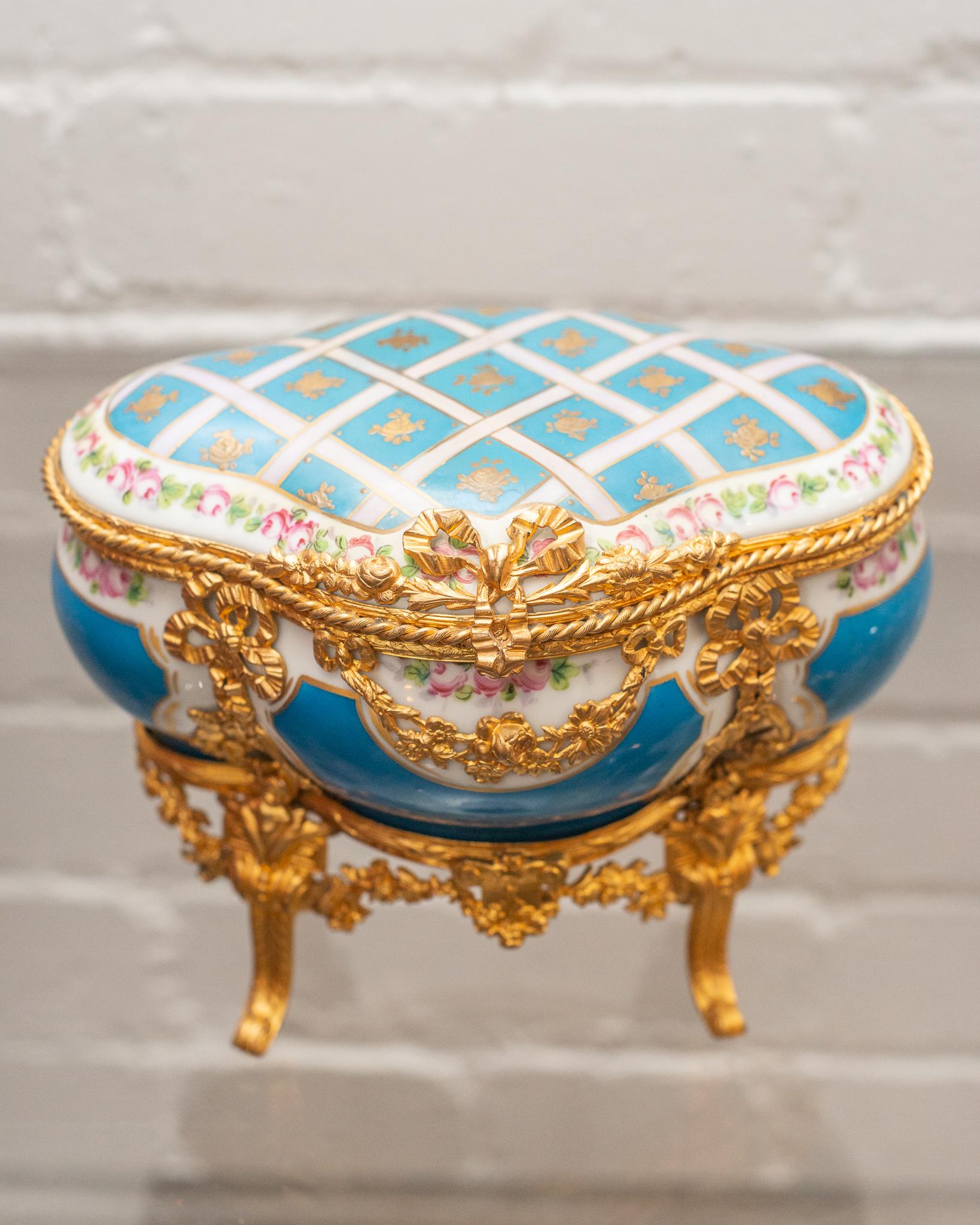 A stunning and ornate Sévres Bleu Celeste jewelry casket with gold ormolu details. Delicately hand painted with flowers, this iconic style of Sévres is timeless and decadent. Bears the crossed sword Sévres marking as well as 