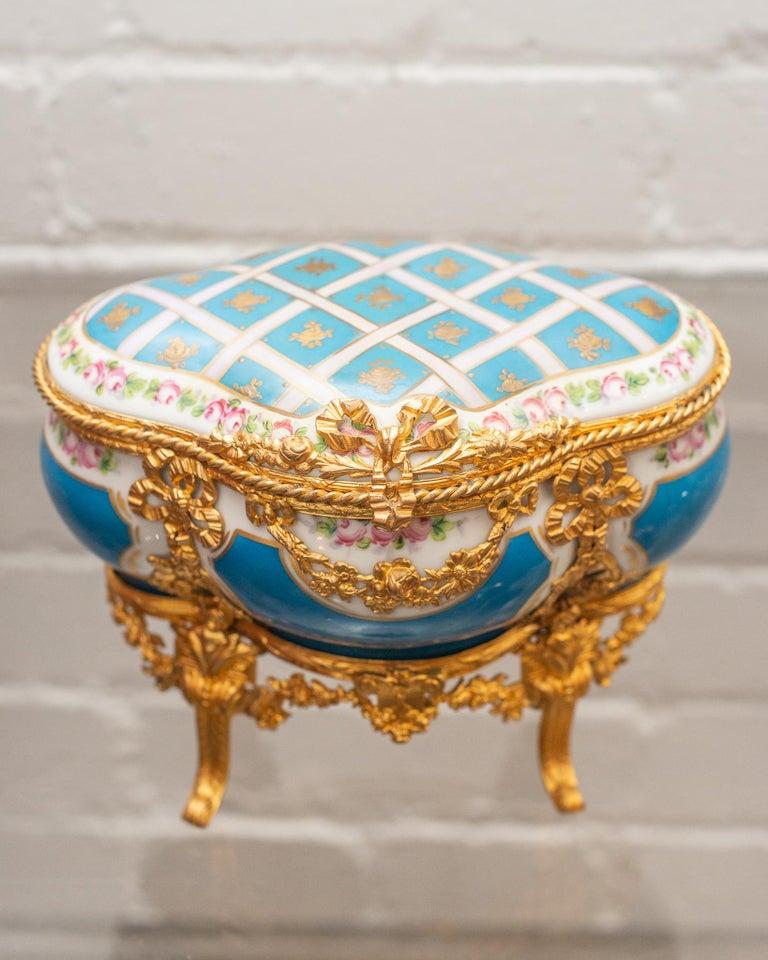 Exemple époustouflant de l'art français, ce coffret à bijoux ancien en porcelaine de Sèvres Bleu Céleste incarne l'opulence et le raffinement. Réalisé dans la glaçure bleu céleste emblématique de la légendaire manufacture de porcelaine de Sèvres, le
