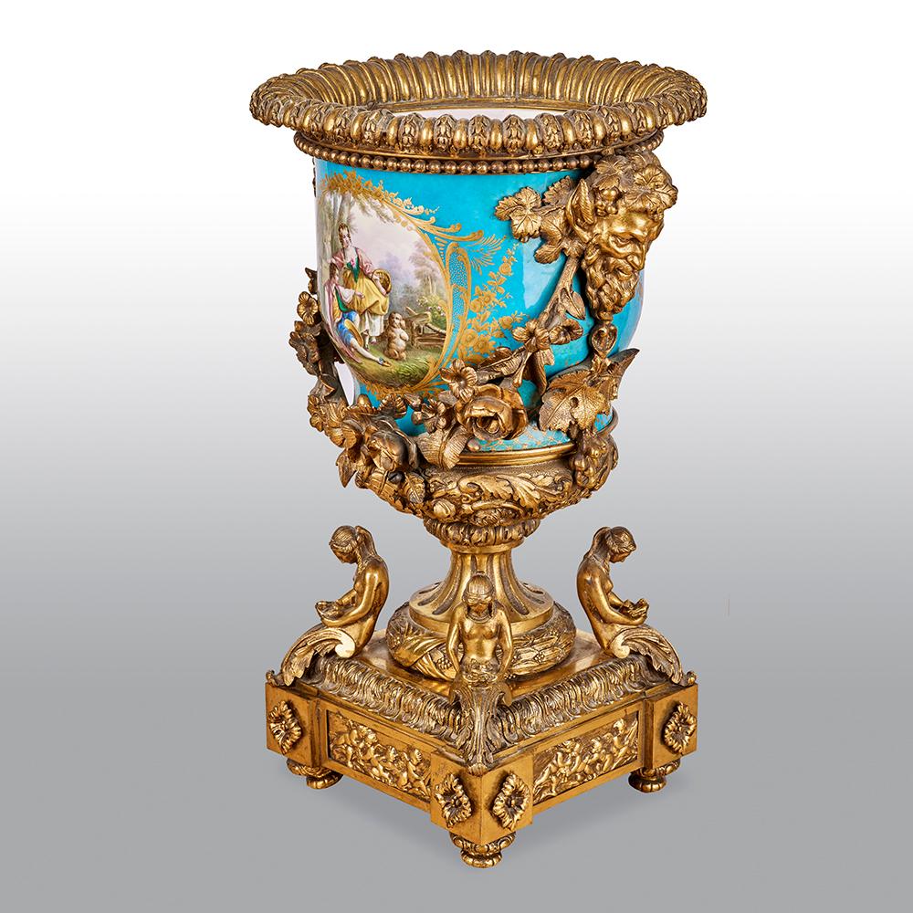 An impressive and large Sevres-style porcelain gilt bronze mounted compote. The porcelain compote vase expertly painted with a classical scene to one side and finished with a botanical painting to the reverse, against a bleu celeste, or sky blue