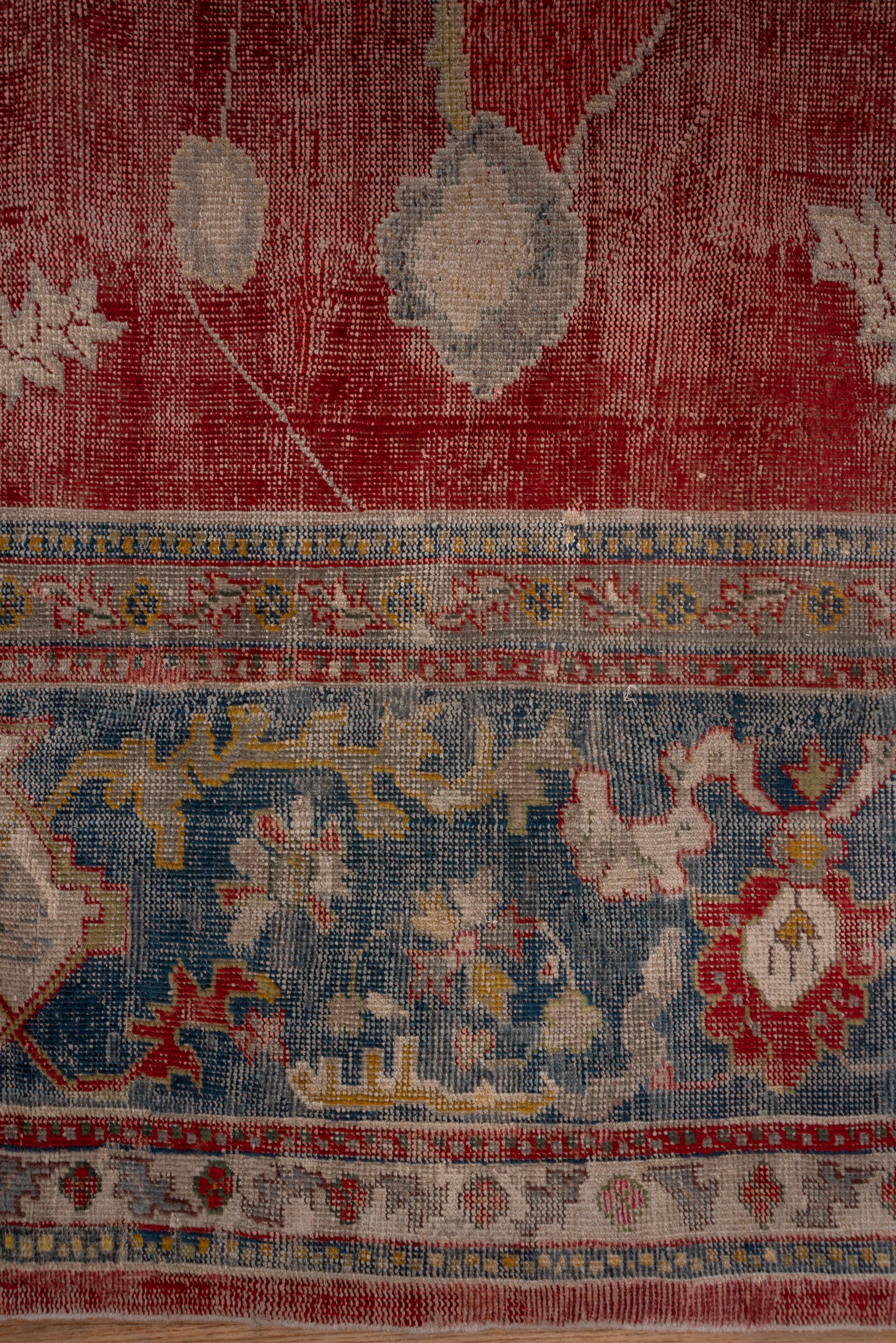The rather worn Turkey red field displays mostly diagonal palmettes connected by stiff vine segments with larger, smoother palmettes at the field ends. The ivory corners are sections of octogram medallions. Te forest green border shows cloud bands