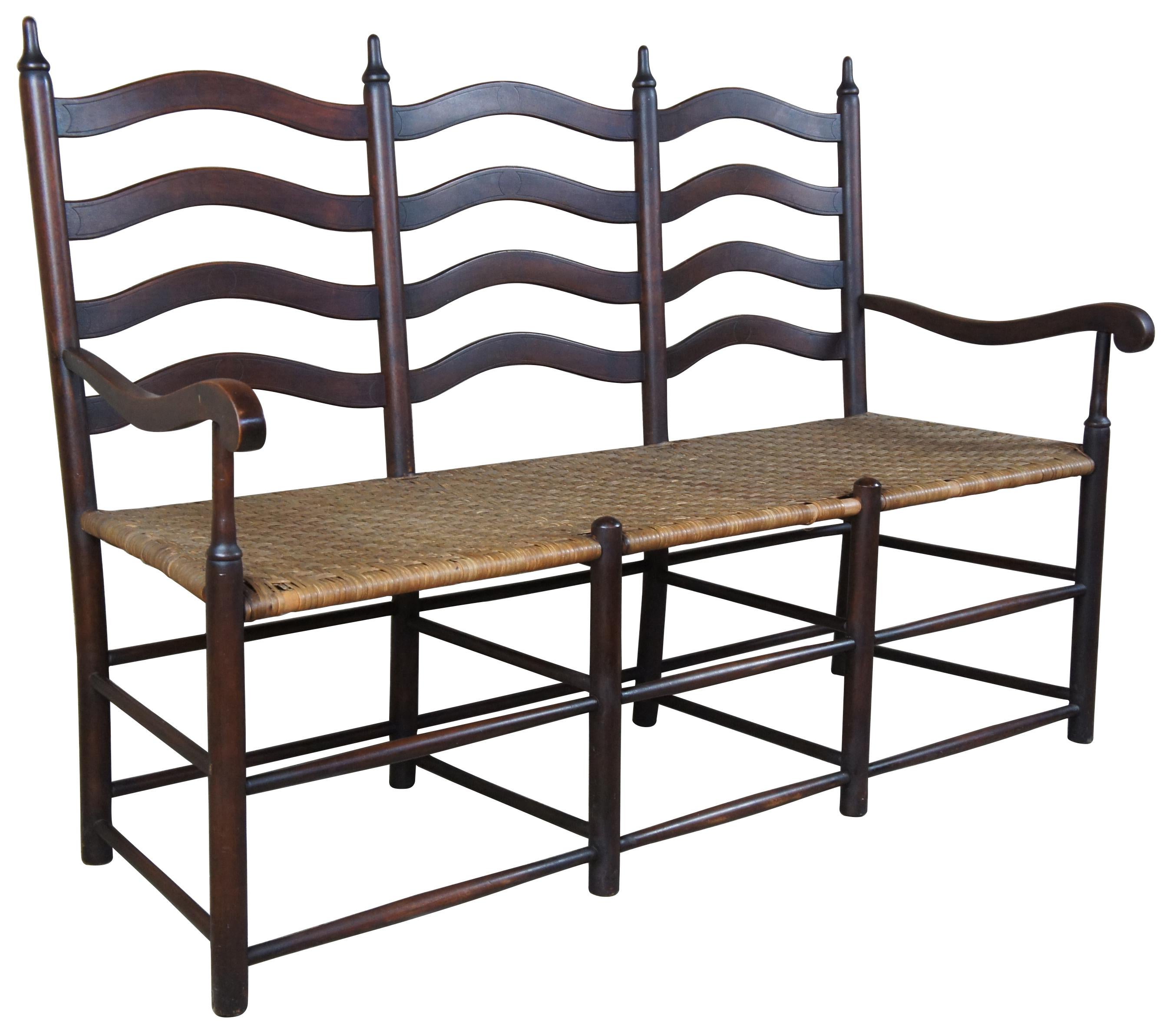 20th century pine Shaker style bench. A three-seat with ladder back design. Features turned finials and rattan seat.
      
