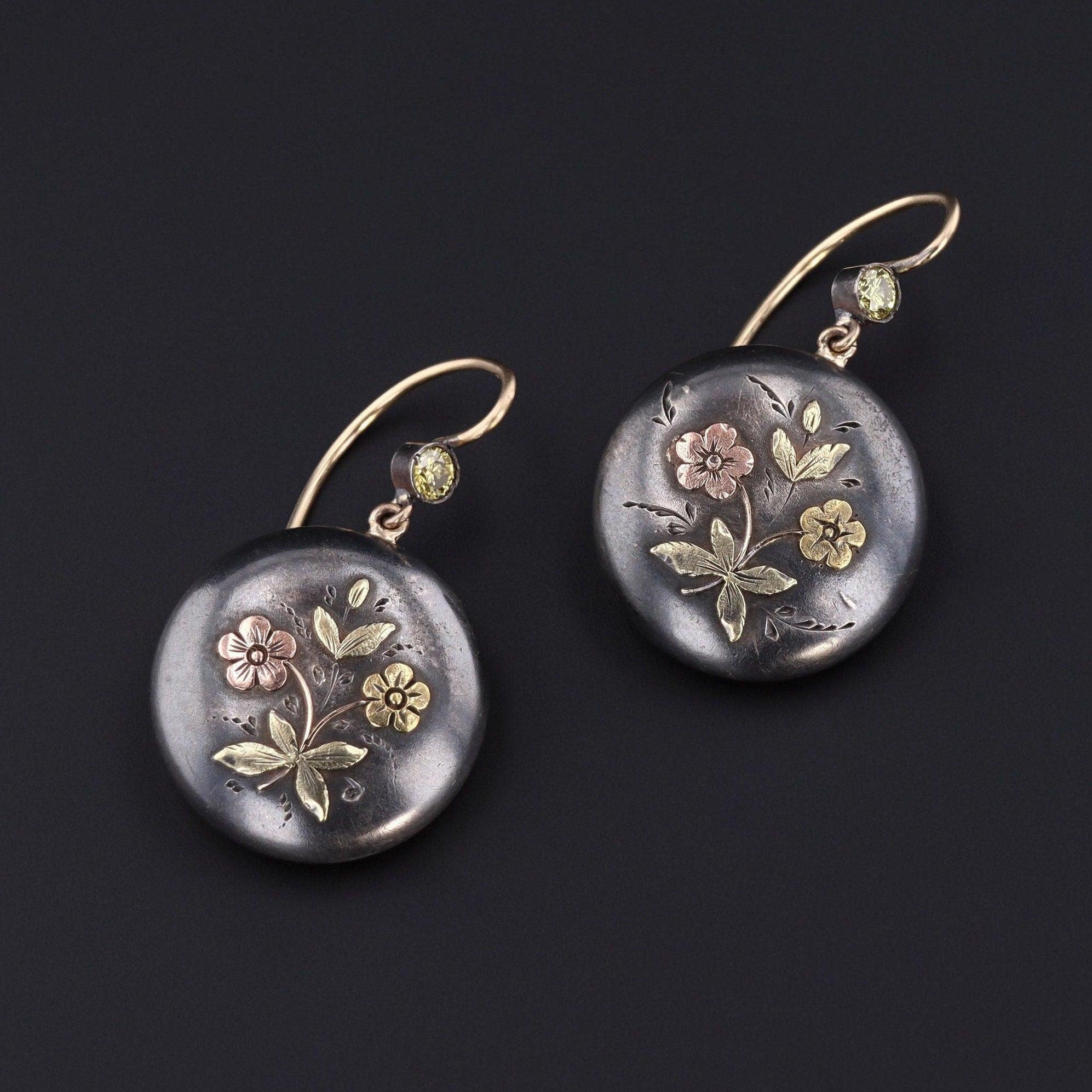 Shakudo is a Japanese mixed metal technique that involved an alloy of copper and gold that was treated to give it a dark black patina.

These antique floral shakudo pieces were converted from silver shakudo cufflinks. Our jeweler added domed 14k