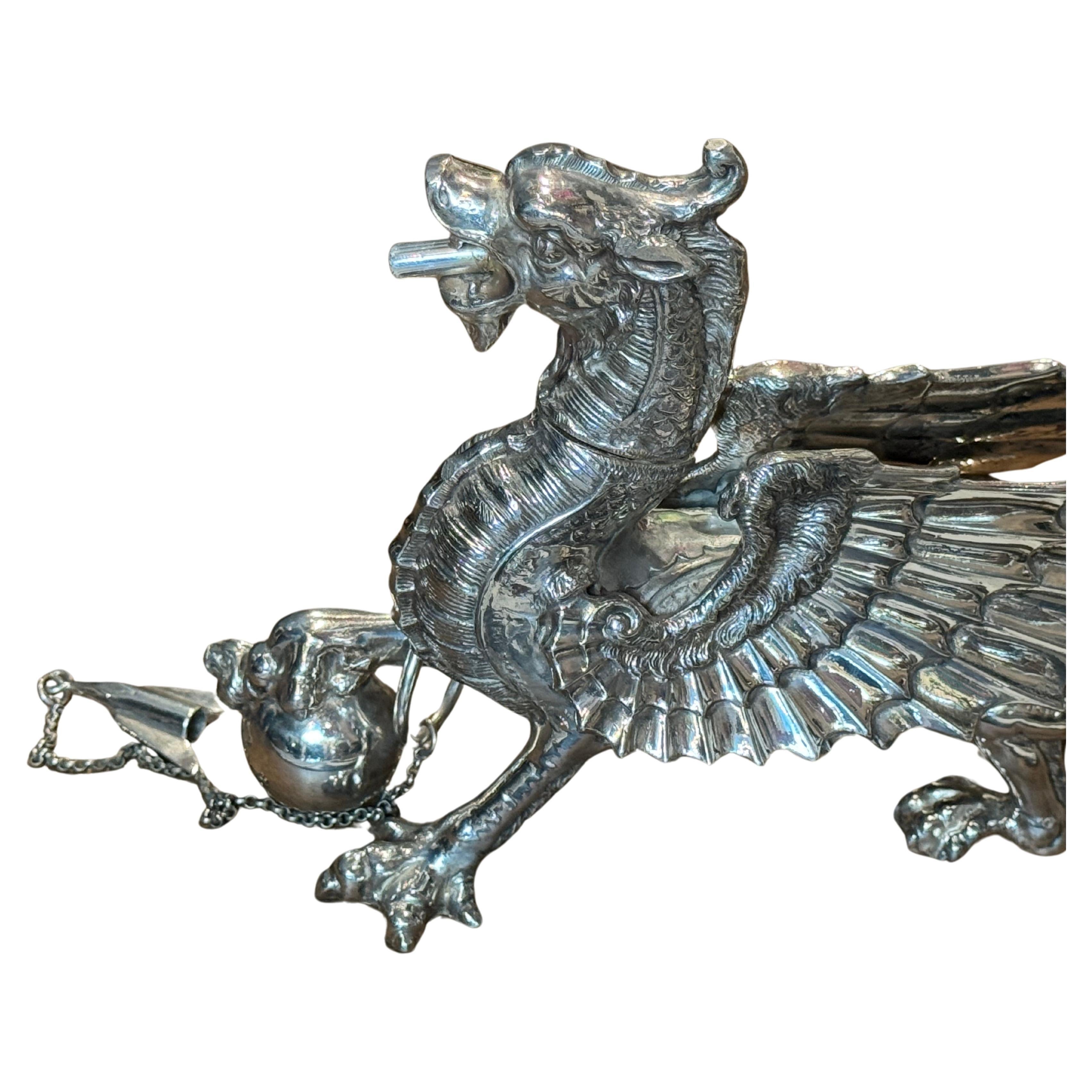 Antiguo encendedor de puros de mesa galvanizado de Sheffield
Esta pieza única y coleccionable presenta un diseño de dragón con cabeza desenroscable, meticulosamente elaborado por Walker & Hall hacia 1900. El cuerpo está hecho con el cuerno de un