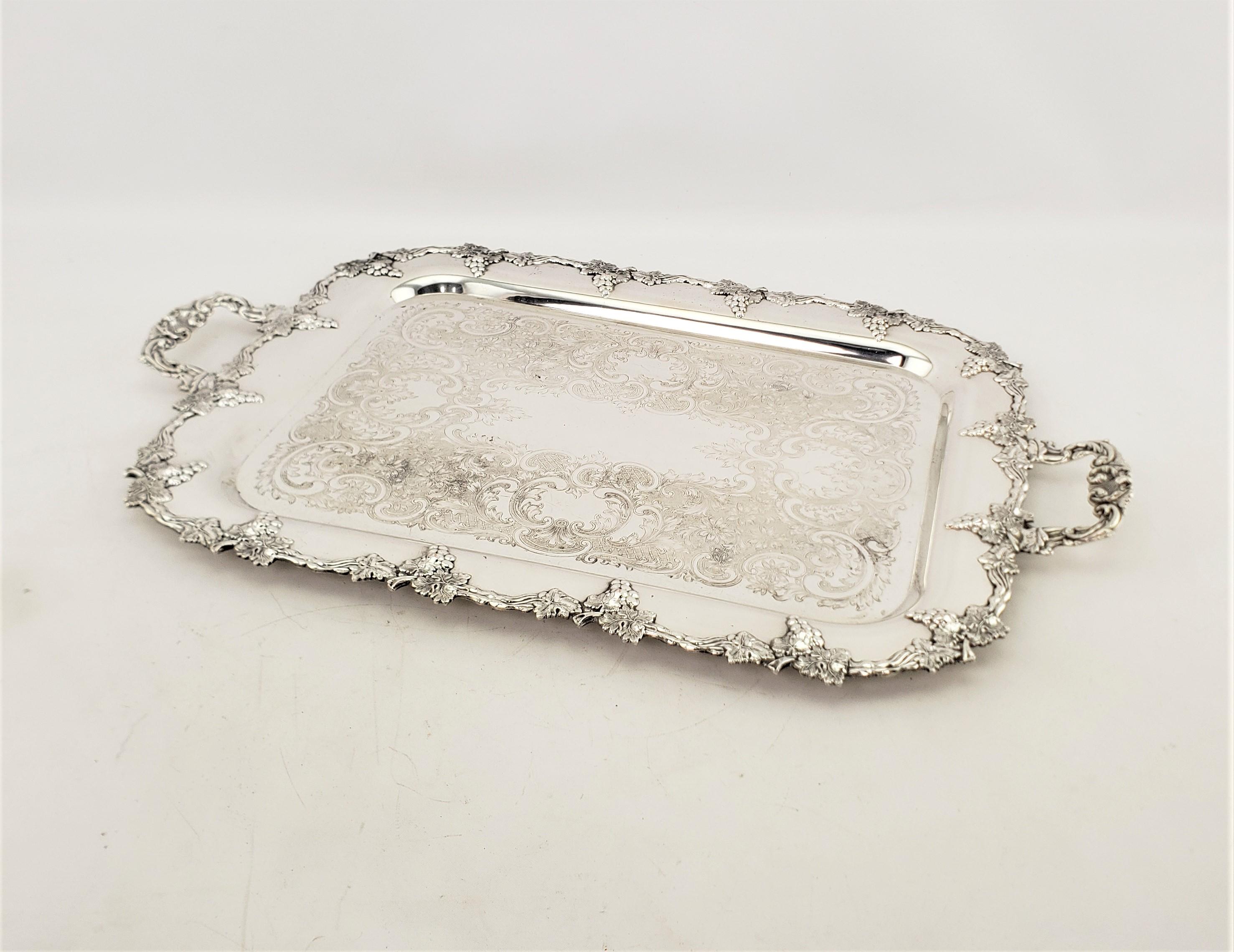 This antique serving tray was made by an unkwown maker and presumed to have originated from England and date to approximately 1920 and done in a Victorian style. The tray is done in silver plate and has applied grape and leaf decoration around the