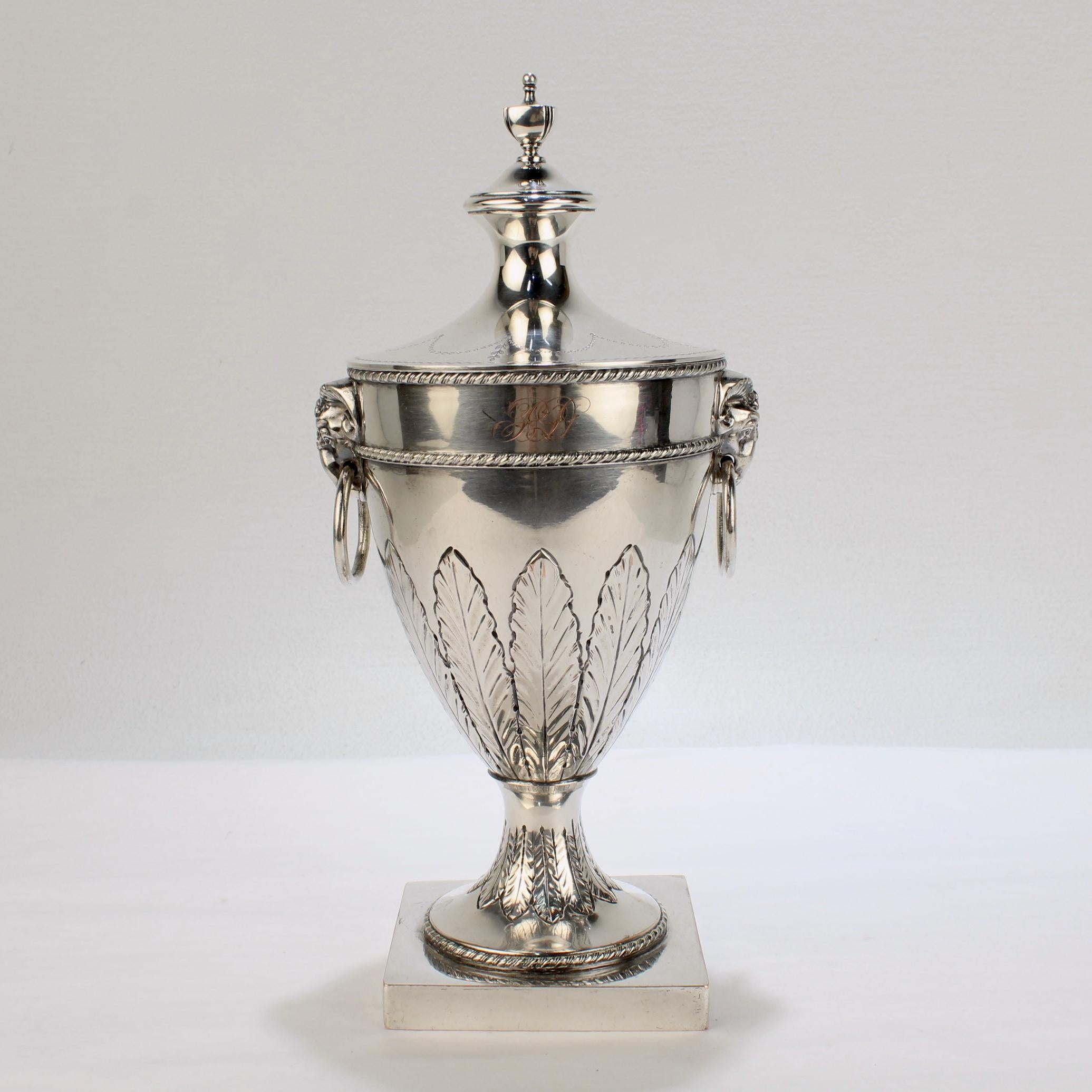 A very fine antique English silver plated vase and cover. 

In the 18th century Neoclassical Sheffield style.

The vase has ram's head and loop handles, etched acanthus leaf design around its circumference, and is supported by a square base. The