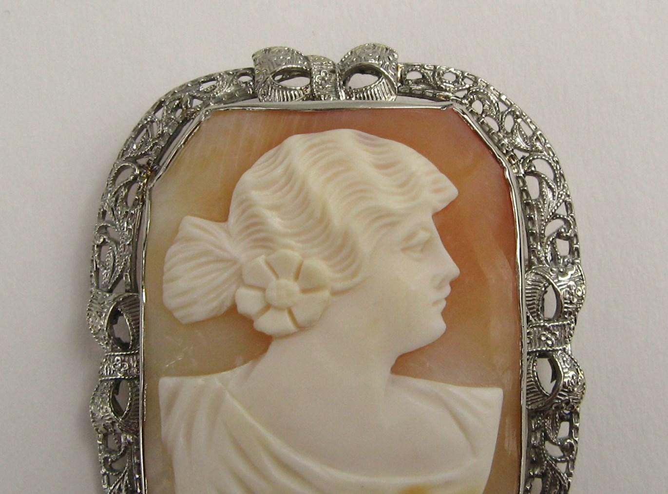 Cameo set in 14K White gold, simply stunning! It has a stunning openwork white gold frame with bow details on all sides. Both a brooch and pendant.  Measuring 1.82 inches top to bottom 1.48 wide.  Hallmarked 14k on the clasp.  Fold down pendant hoop