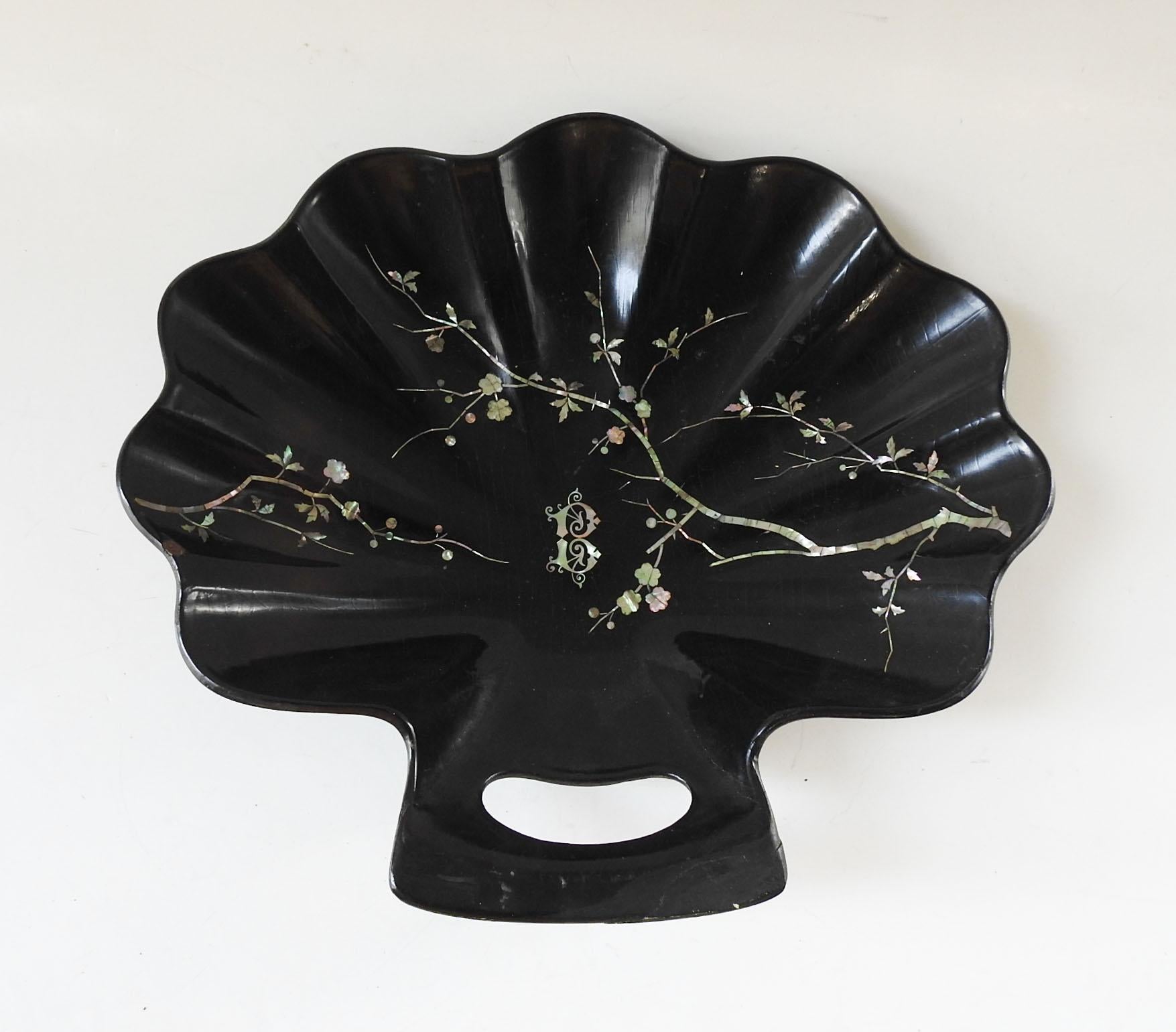 Circa 1890's black paper mache crumb tray.  Scalloped shell shape with mother of pearl inlay in cherry blossom pattern and the letter B.  No markings, repainted repaired handle corner and a small surface edge chip, overall craquelure.