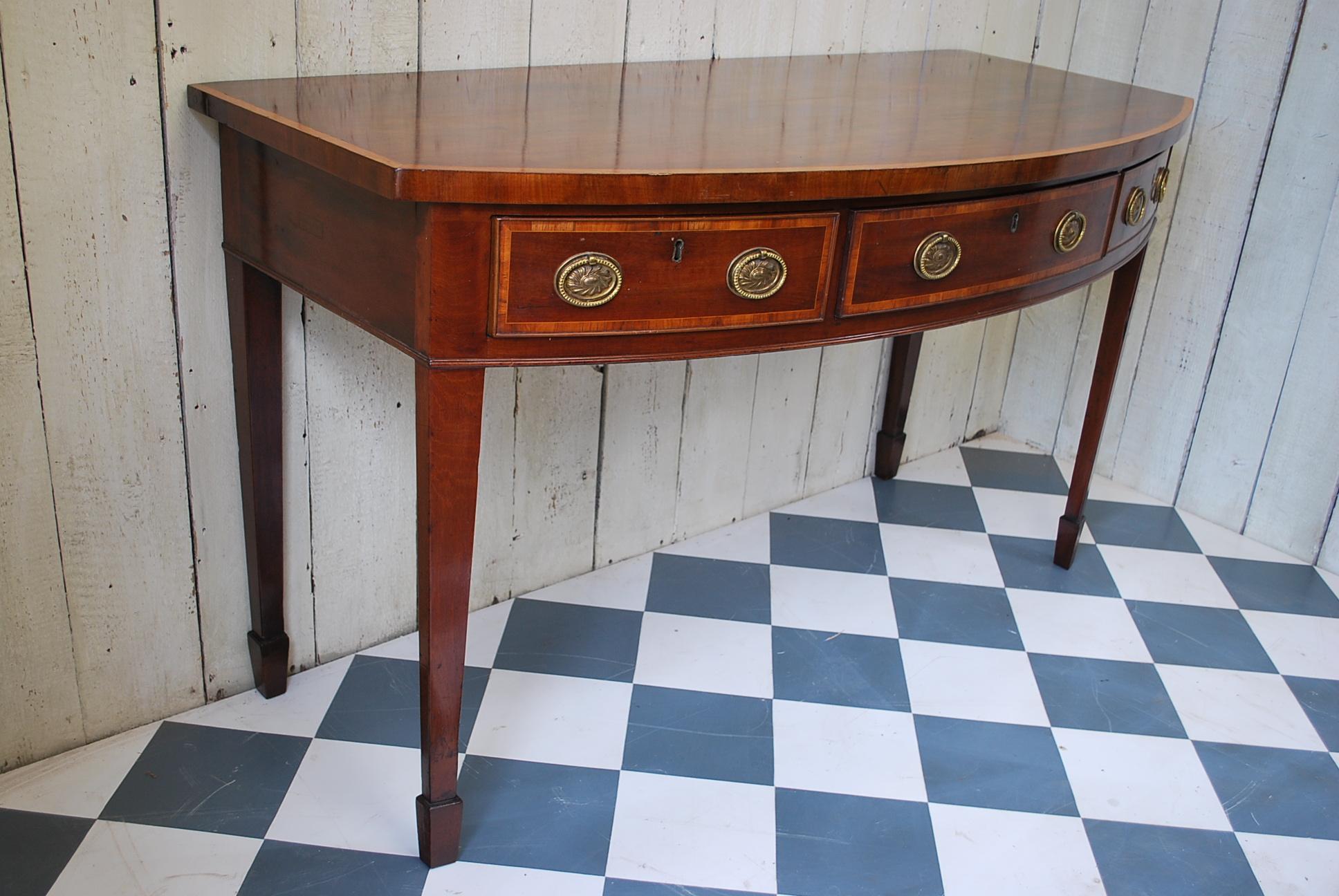 Beautiful mahogany Sheraton period bow front serving table/hall table, of excellent proportions. Standing on tapered legs with spade feet, cross banded in contrasting satin wood. The drawers have original oak linings and gilded brass period