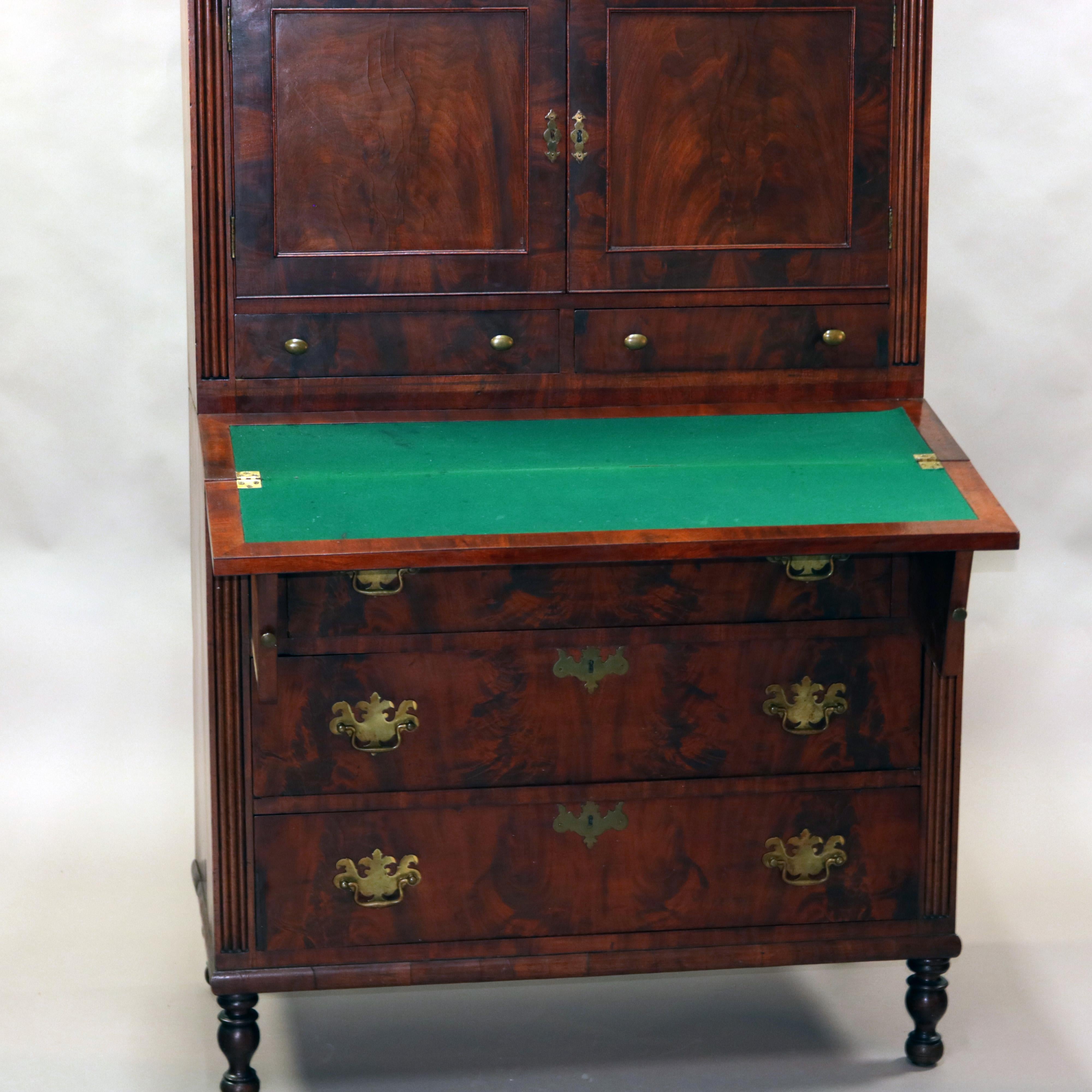 An antique Sheraton Tambour secretary offers deeply striated mahogany construction with upper double door cabinet over two lower drawers and surmounting cas with drop front desk and three long drawers, raised on turned feet, circa 1830

Measures: