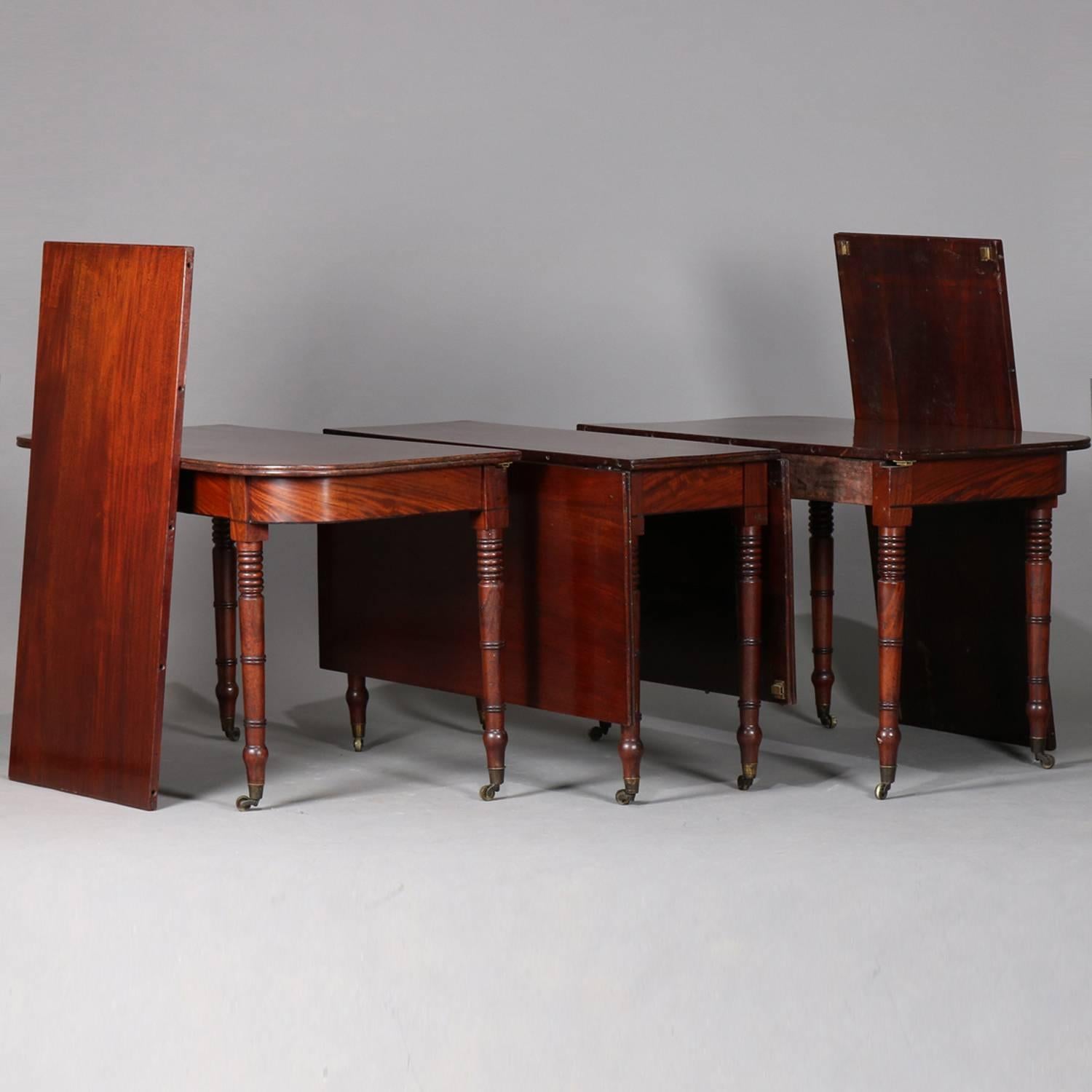 Antique Sheraton flame mahogany banquet table features top with reeded edging over skirt and seated on turned legs with castors, includes two demilune sections and a drop leaf section and has two leaves, circa 1820

Measures: 28.5