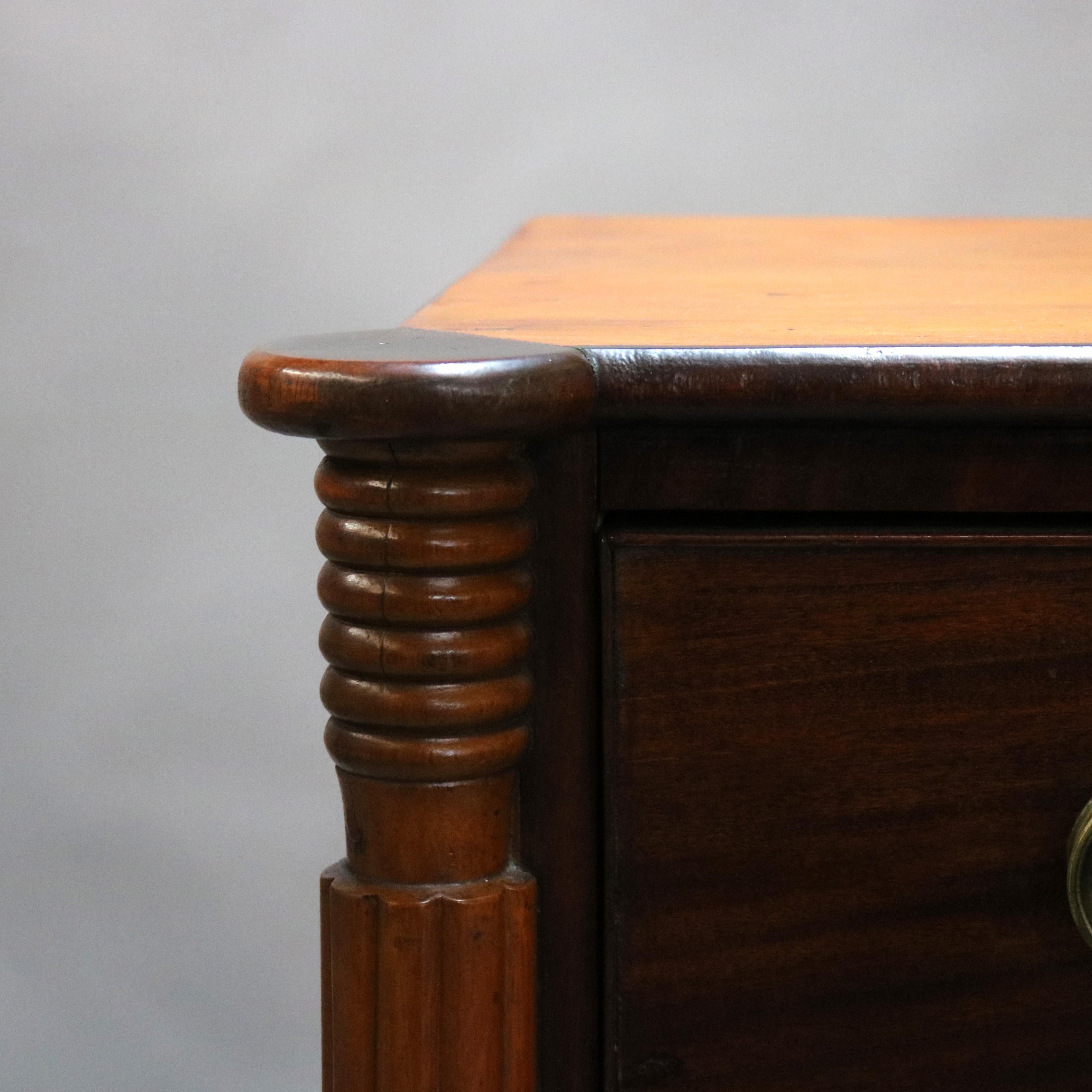 An antique Sheraton chest of drawers offers mahogany and cherry construction with shaped top over four long drawers flanked by reeded columns and raised on turned legs, c1830.

Measures: 42.25