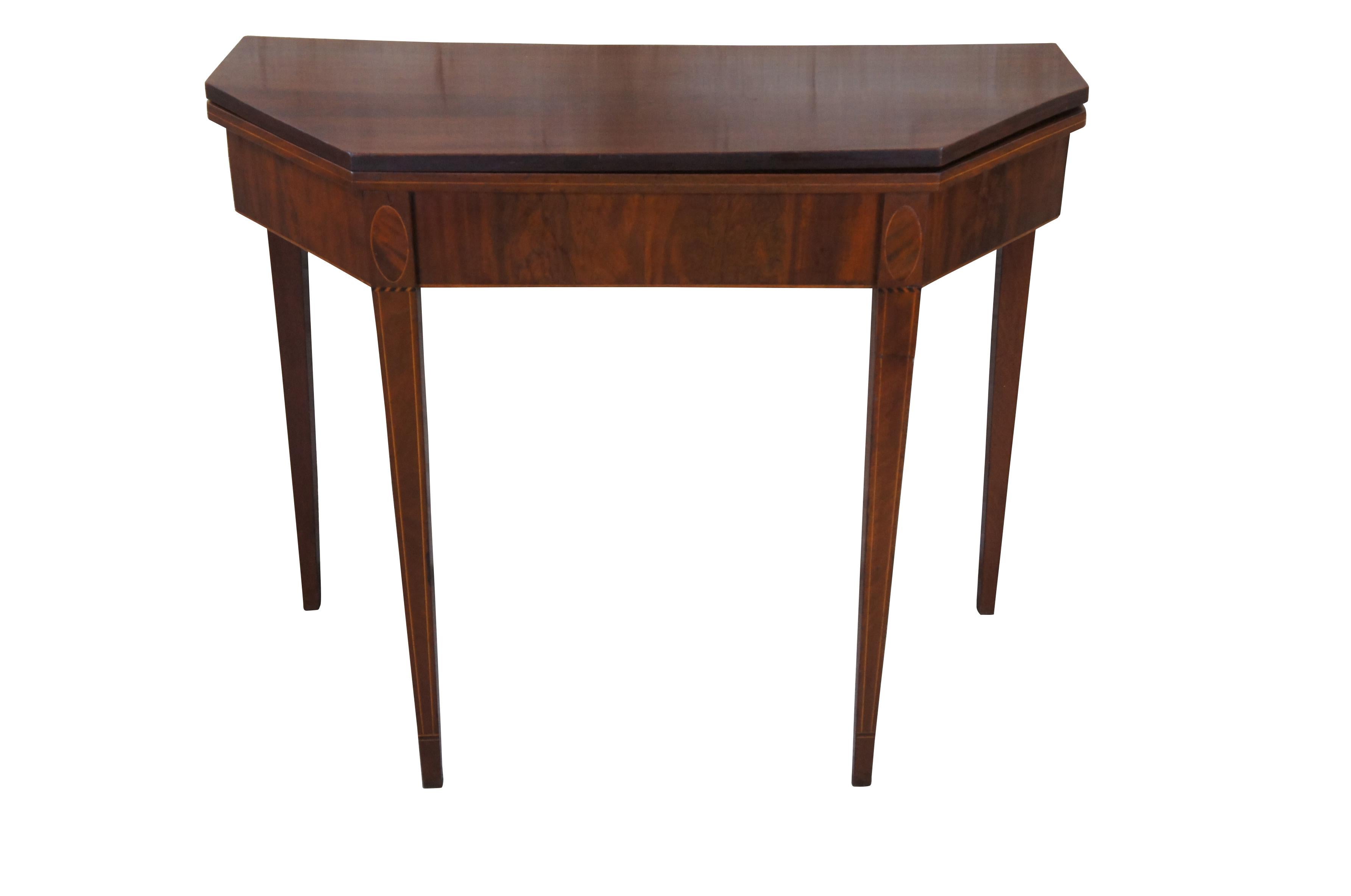 Antique Sheraton period card or game table, circa 1790-1820.  Made from mahogany with crotch mahogany veneer, featuring an inlaid flip top octagonal demilune top supported by square tapered legs.  Each leg showcases oval inlay over striping and