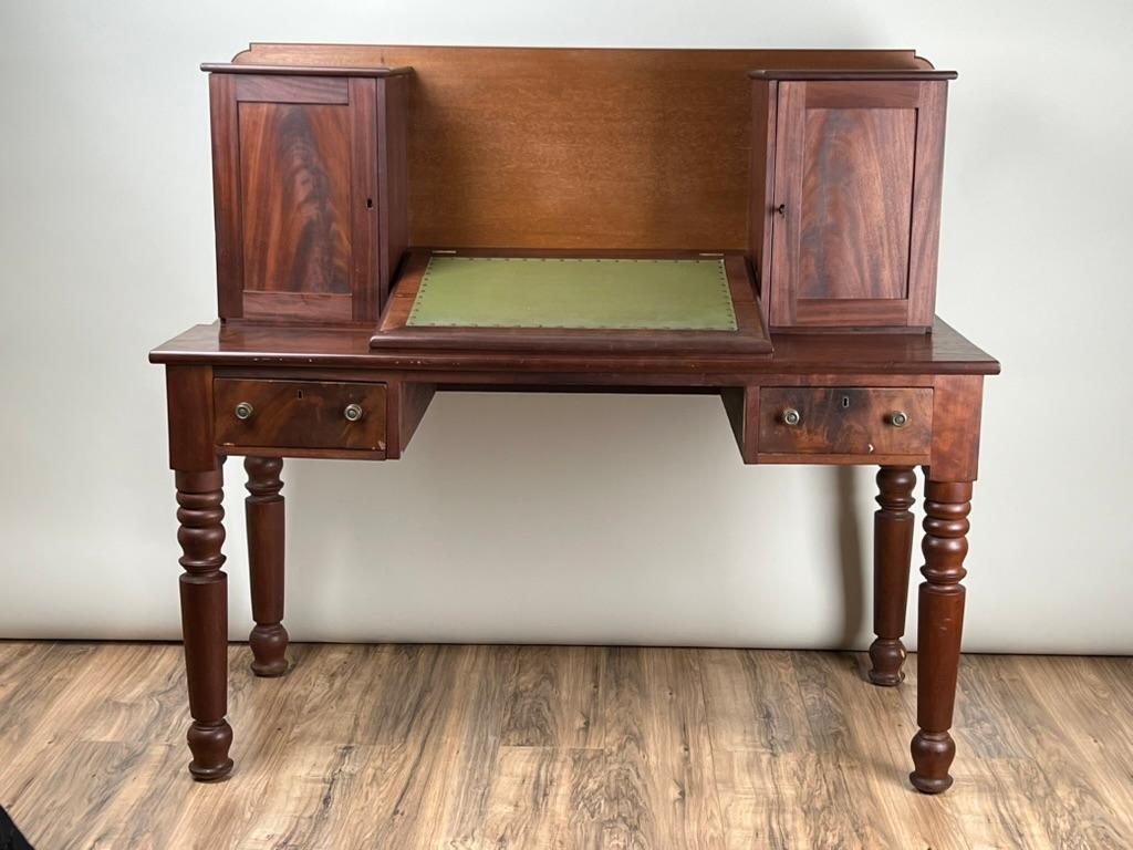 Questa rara e splendida credenza da piantagione Sheraton della metà del XIX secolo unisce il fascino del Sud a un design pratico. Realizzata in mogano riccamente scolpito, la scrivania presenta un'audace forma rettangolare con un'alta spalliera e