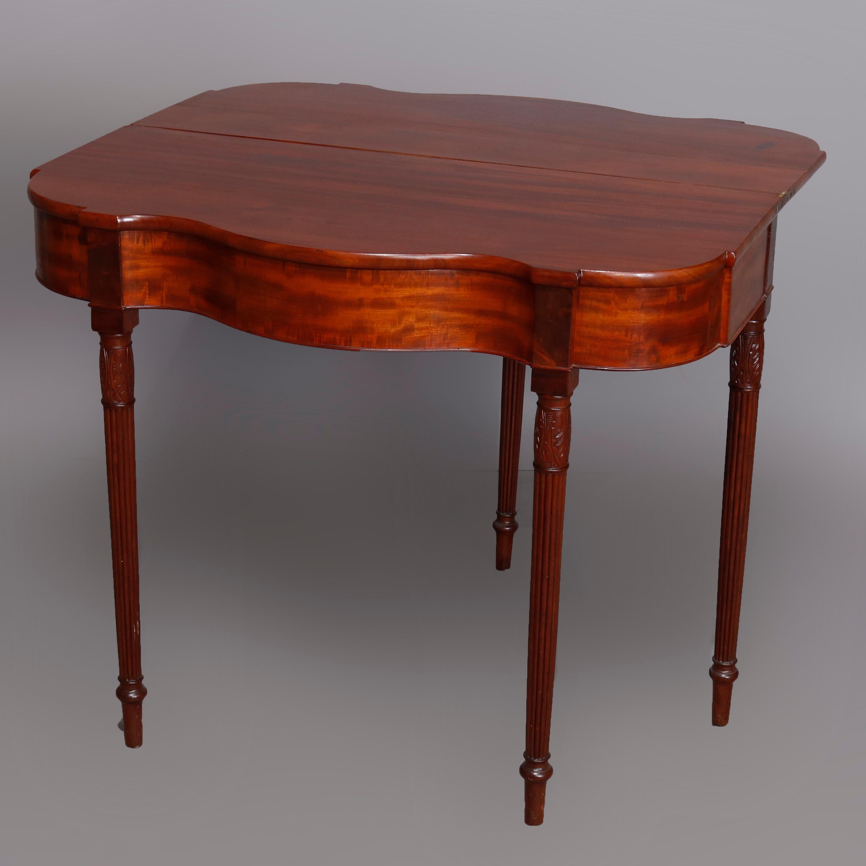 An antique Sheraton game table offers flame mahogany construction having shaped flip top with serpentine skirt and raised on turned legs, circa 1810

***DELIVERY NOTICE – Due to COVID-19 we are employing NO-CONTACT PRACTICES in the transfer of