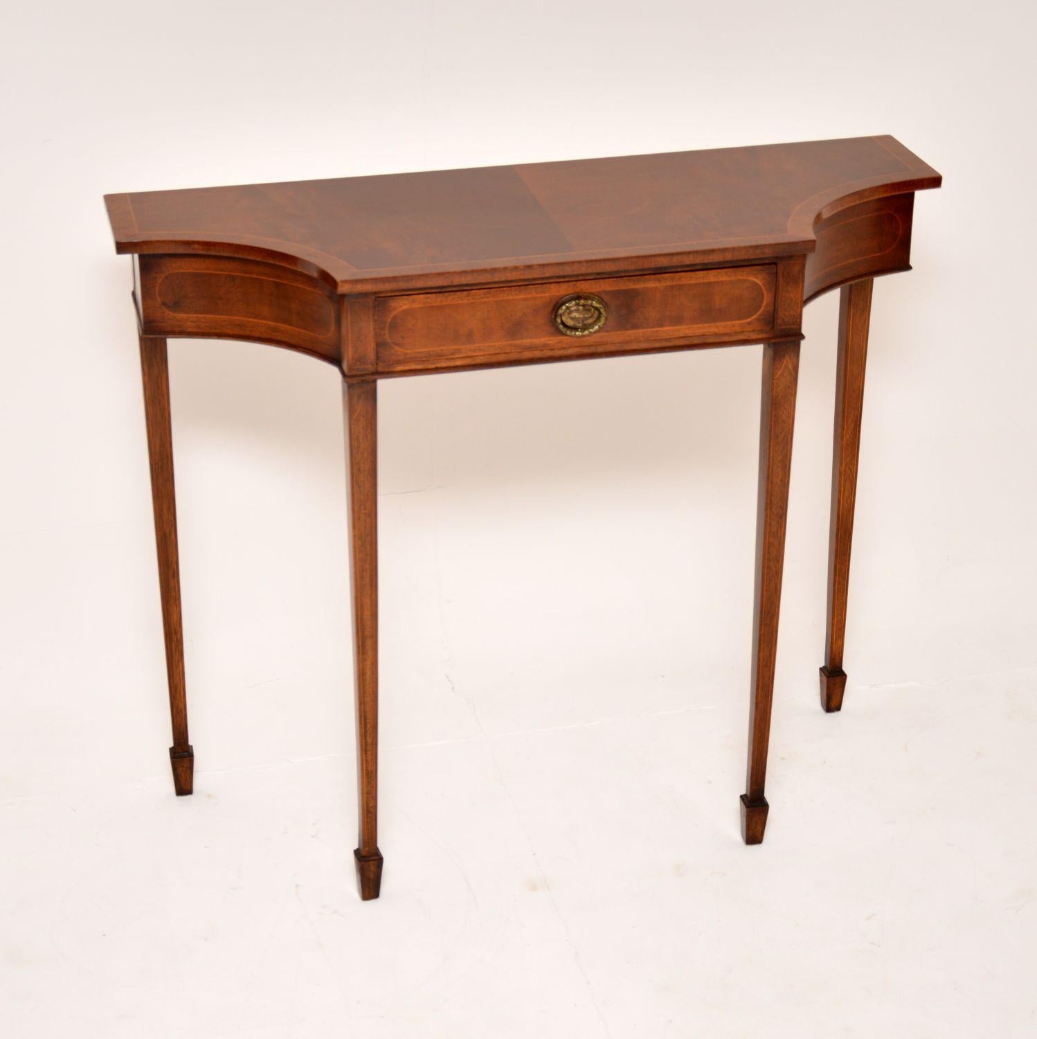 A beautiful and elegant antique console table in the Sheraton style. This was made in England, it dates from around the 1950’s.

The quality is excellent, this has a fine and sturdy build. The shaped top has a single drawer and sits on tapered