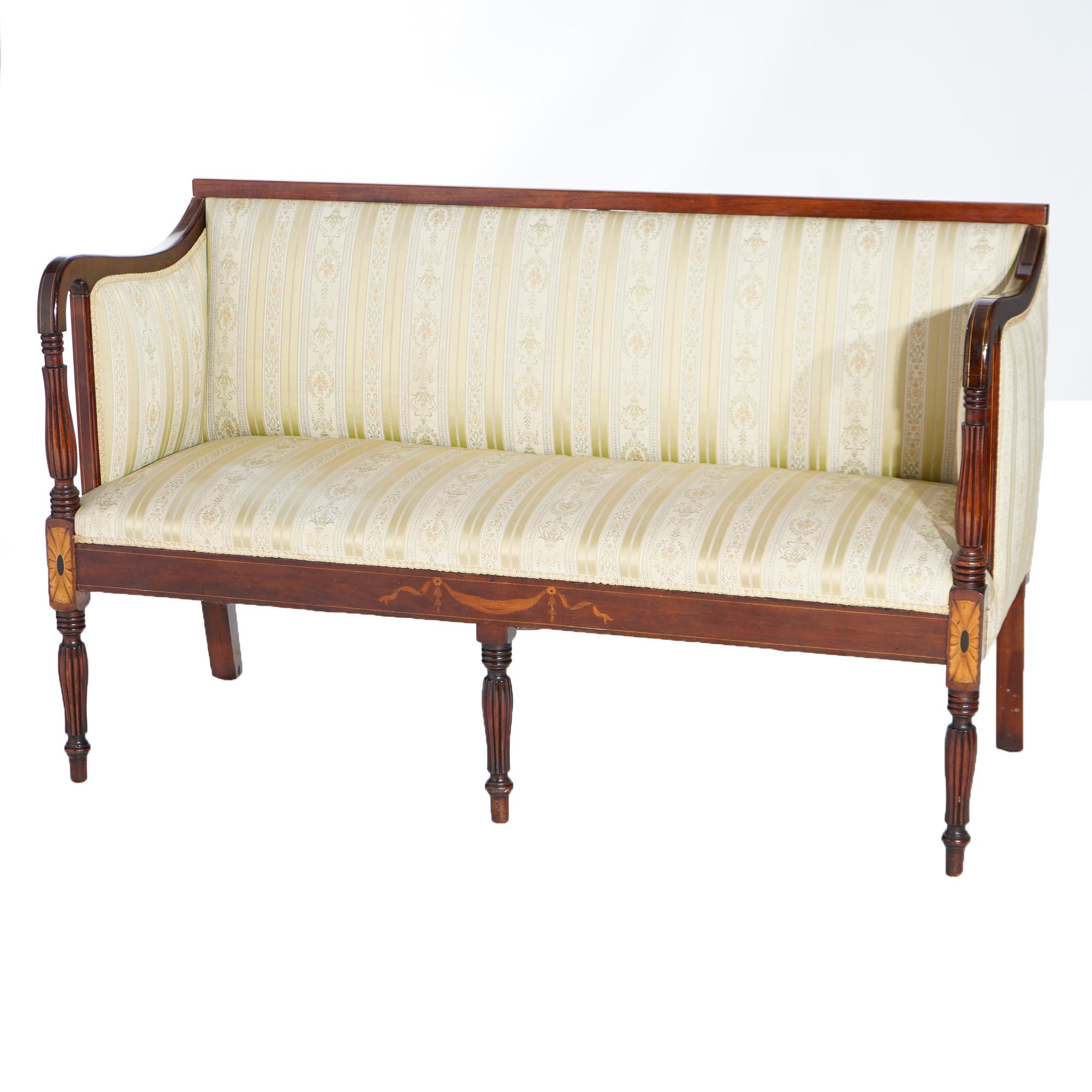 An antique Sheraton settee offers mahogany frame with upholstered back, sides and seats, curved arms with turned supports, satinwood inlaid patera and raised on turned legs, 19th century

Measures- 34.25''H x 54.5''W x 23.5''D; seat height 17.5
