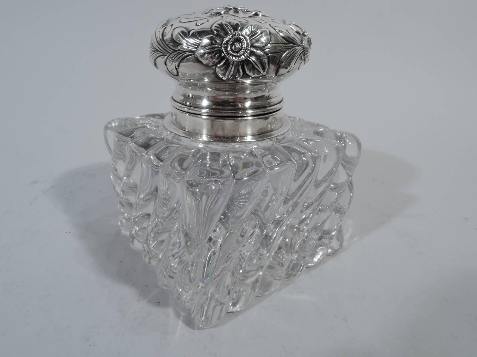 Pretty sterling silver and glass inkwell. Made by Shiebler in New York, circa 1900. Square clear glass with twisted flutes. Star cut to underside. Short neck with sterling silver collar and hinged bun cover. Pretty chased and repousse flowers on